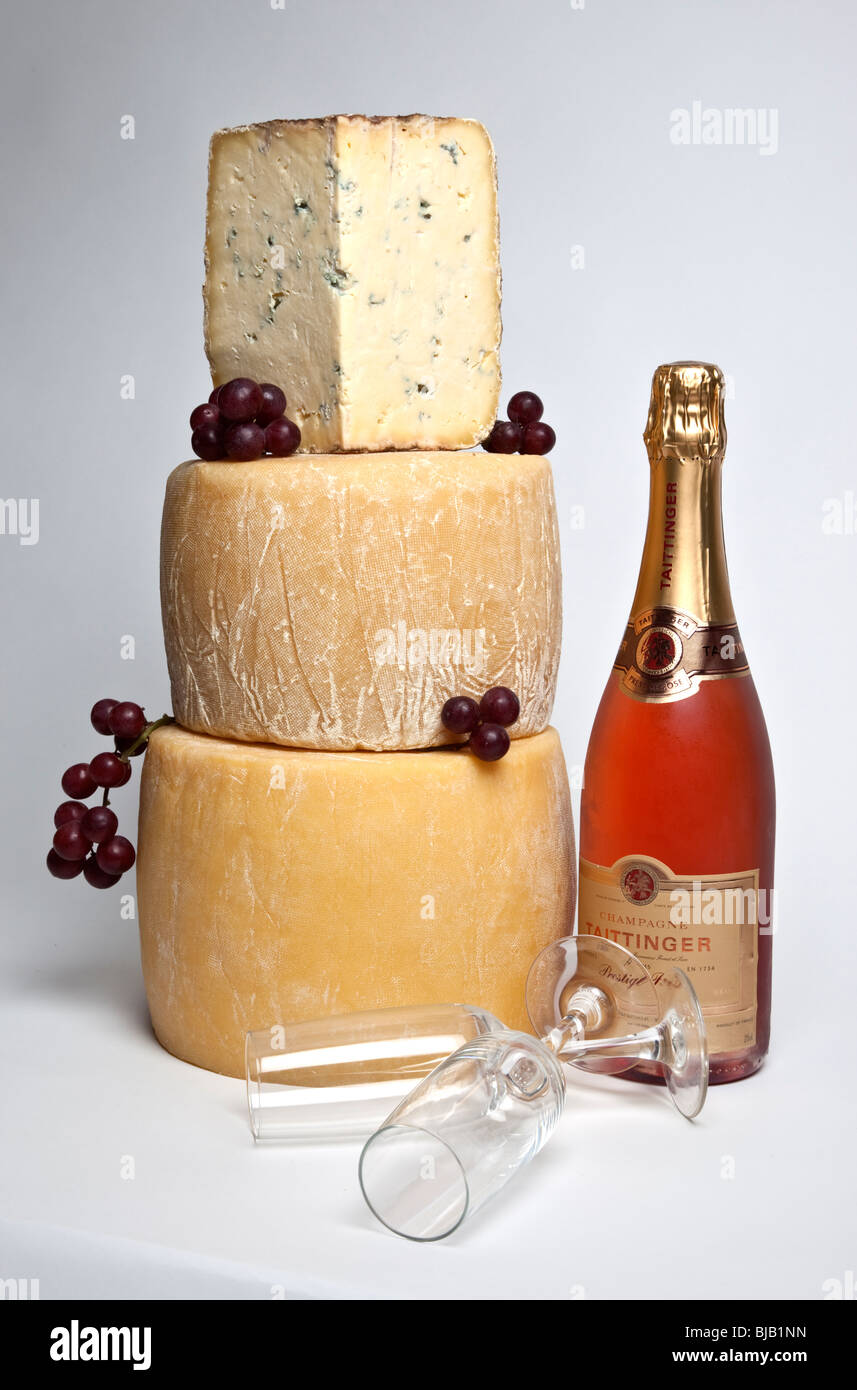 Una celebrazione torre di tutto il round di formaggi con una grande fetta di formaggio blu con una bottiglia di champagne rosato e due bicchieri Foto Stock