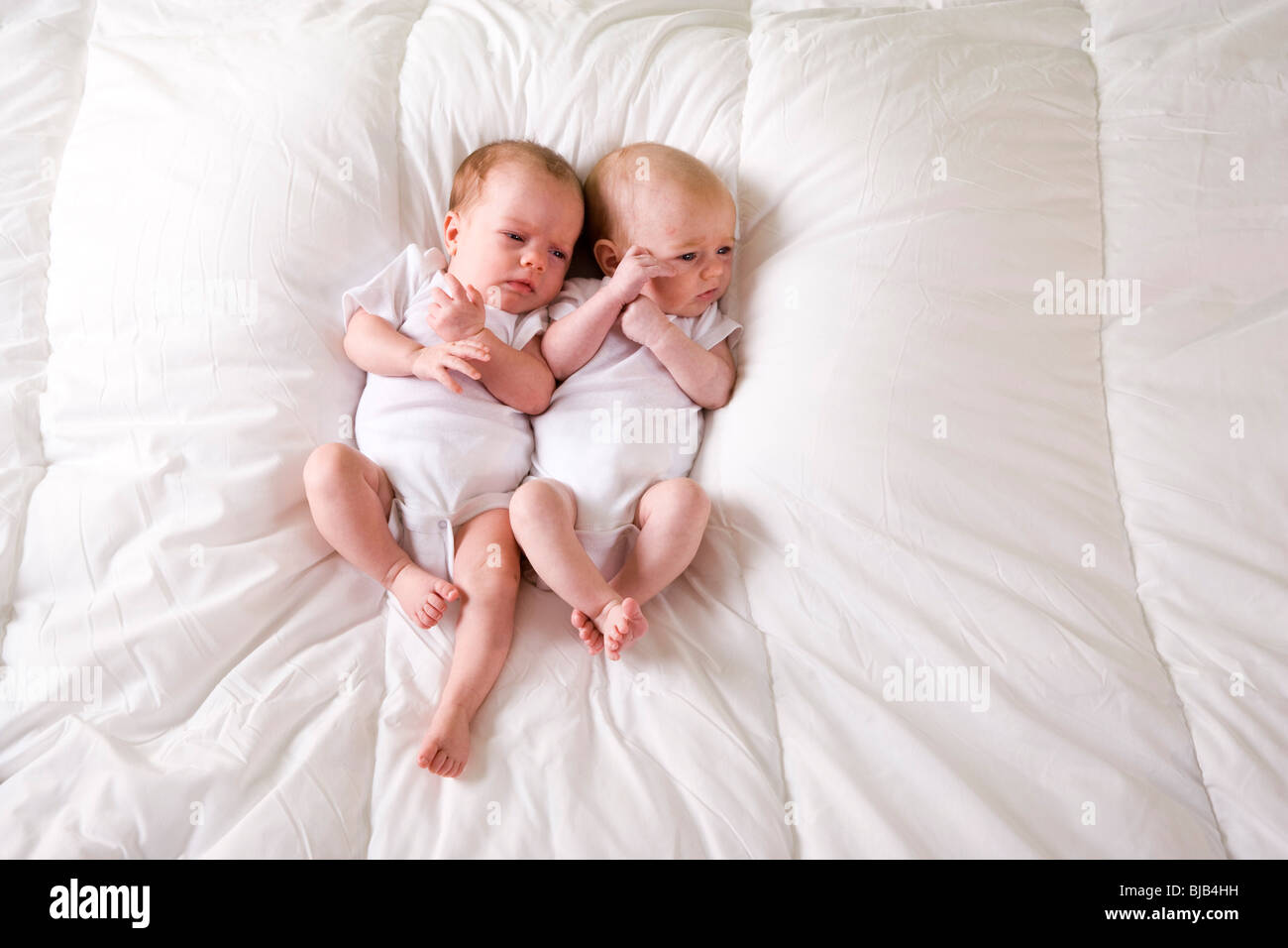 Twin Neonato Neonati affiancati sulla soffice coltre bianca Foto Stock