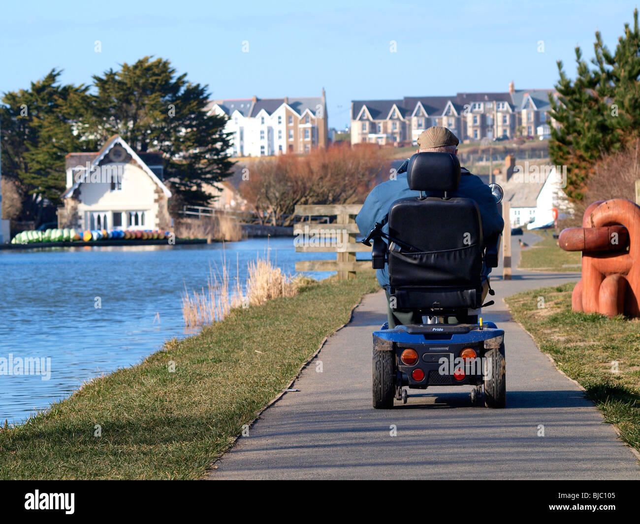 Il vecchio uomo su una mobilità scooter a cavallo lungo il percorso del canale, Bude, Cornwall Foto Stock