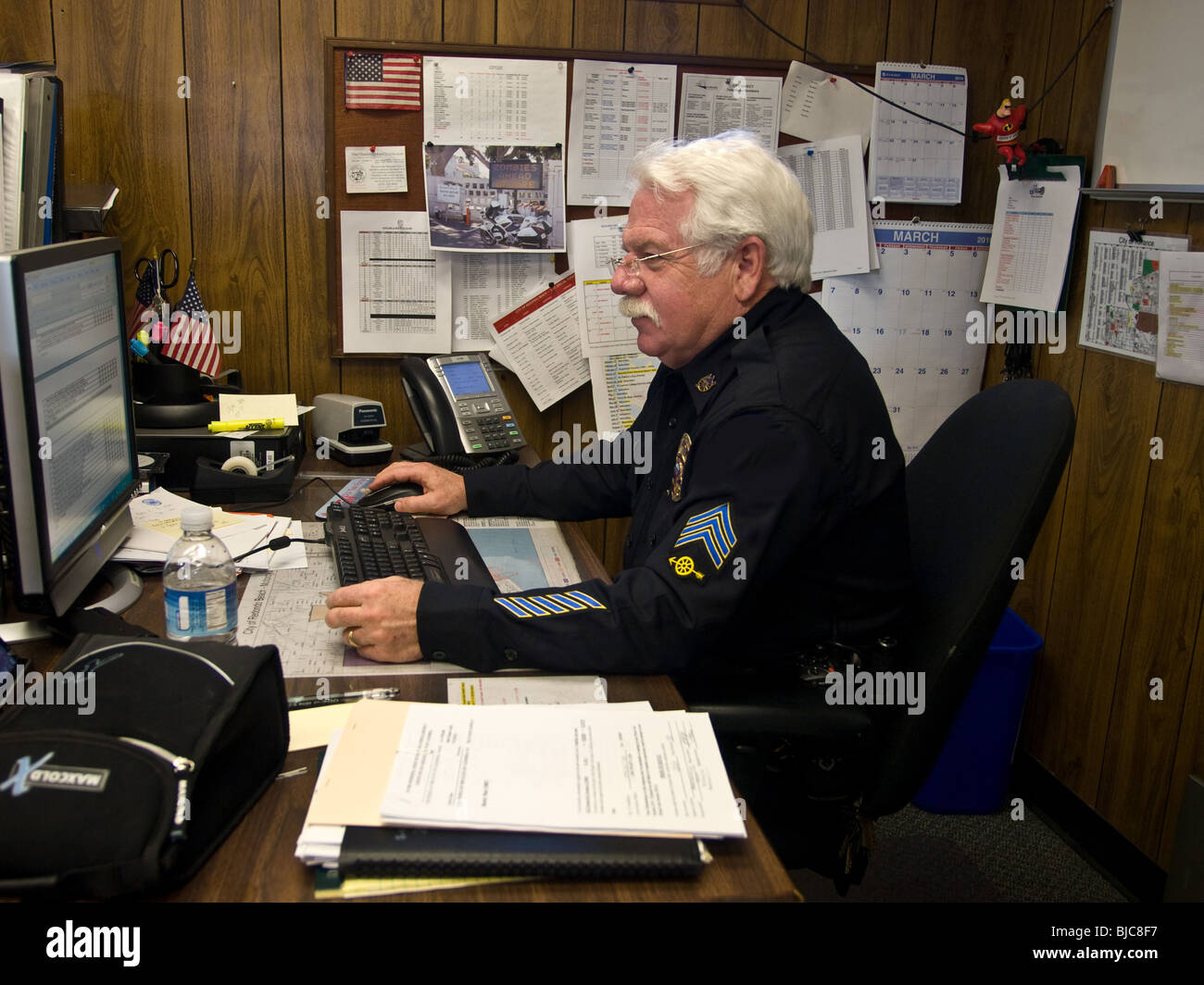 Senior Sargent di polizia a lavorare alla sua scrivania Foto Stock