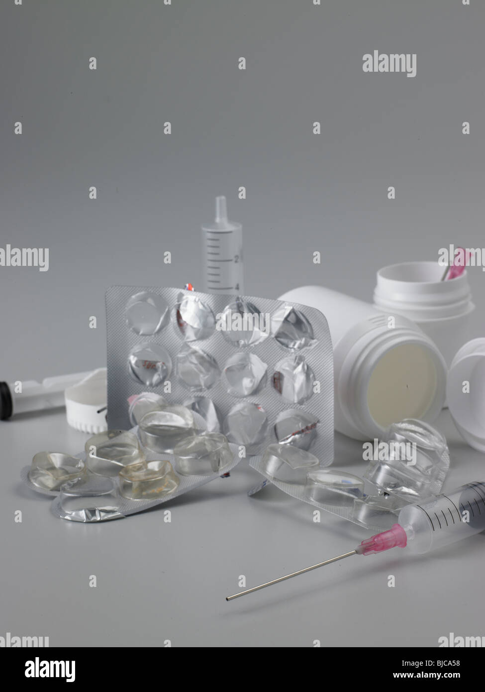 Rifiuti di imballaggio prodotti farmaceutici e la siringa con plastica bianco flaconi portapillole shot in formato verticale con due siringhe Foto Stock