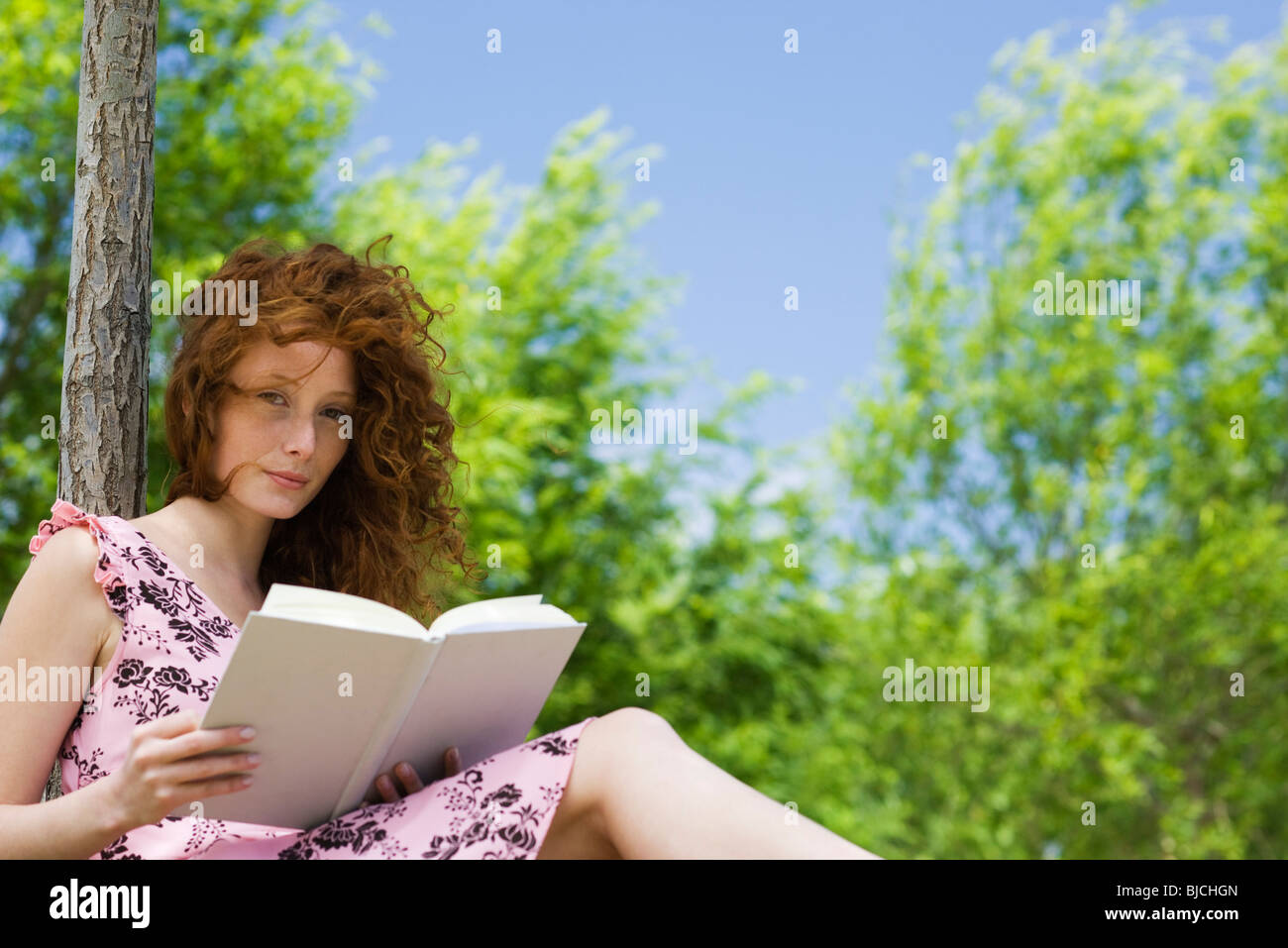 Giovane donna lettura all'aperto, ritratto Foto Stock