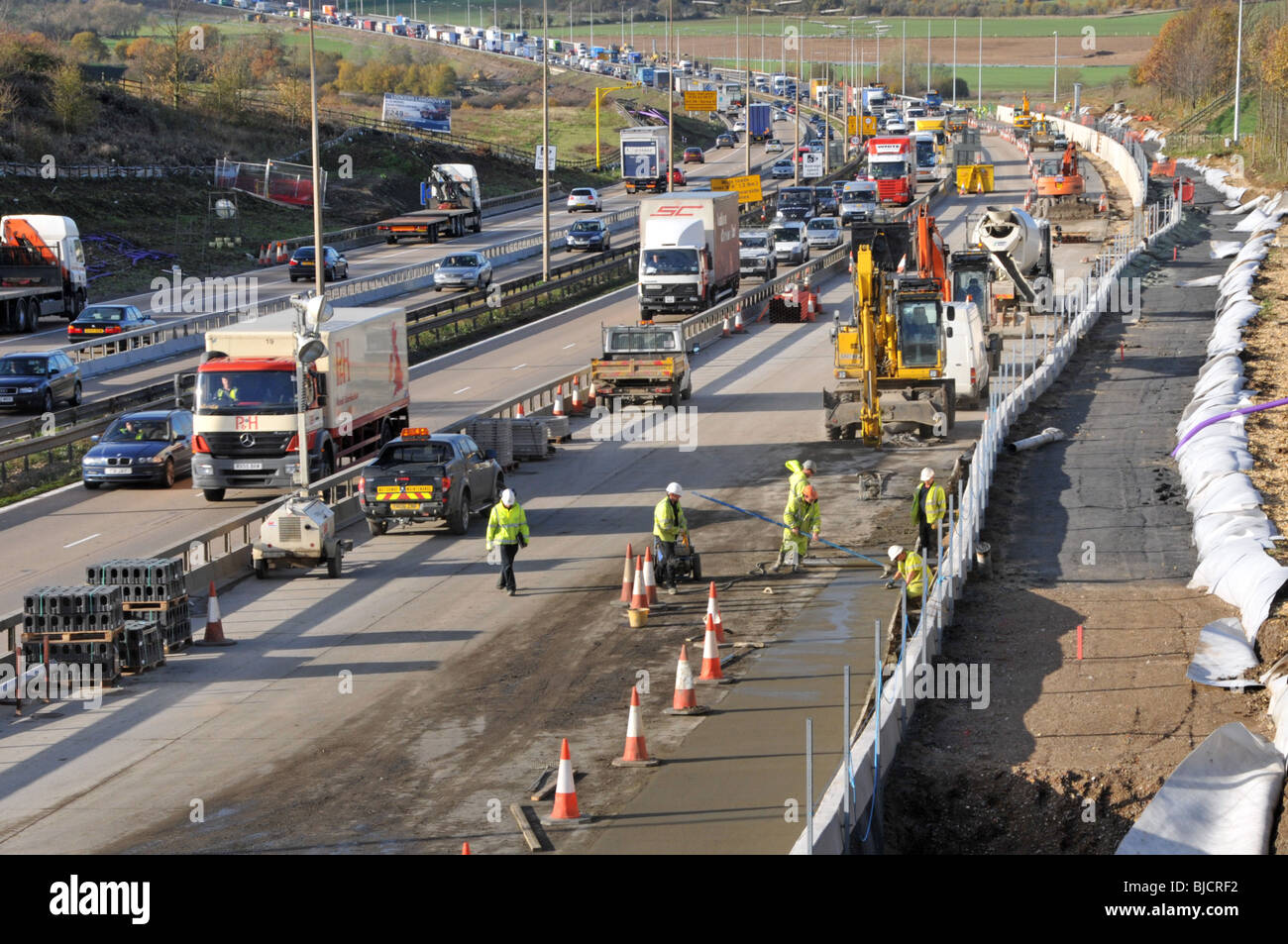 Ingegneria civile lavori stradali lavoratori edili e macchine che lavorano in cantiere M25 costruzione di un'autostrada a quattro corsie totale Essex paesaggio Inghilterra Regno Unito Foto Stock