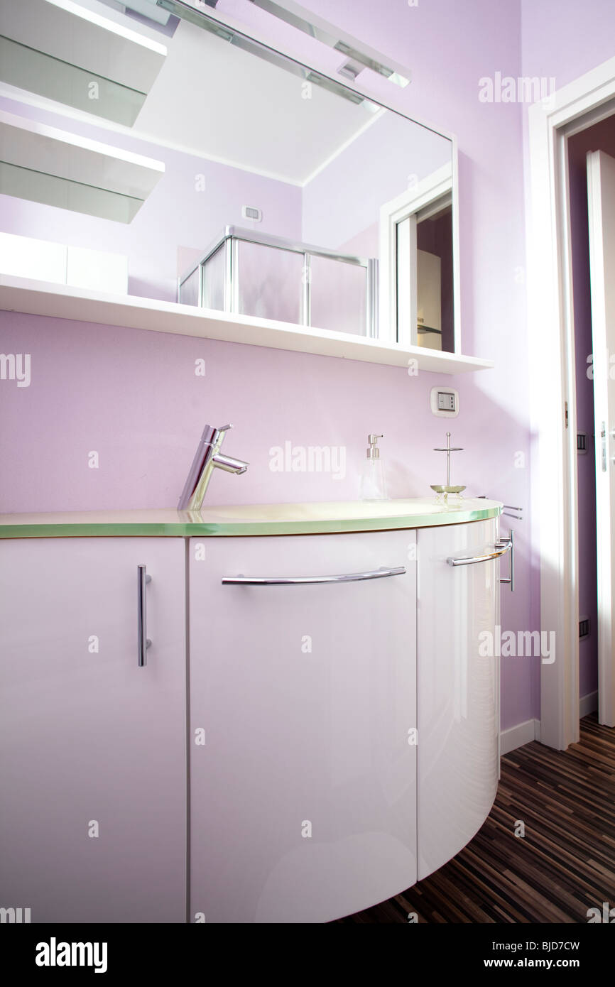 Il bagno era di colore rosa con parete con lucido armadi lucidato e pavimento in legno duro Foto Stock