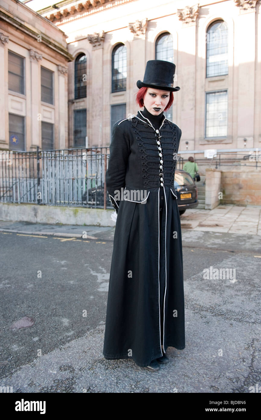 Scary giovane donna in top hat e lungo cappotto nero Foto Stock