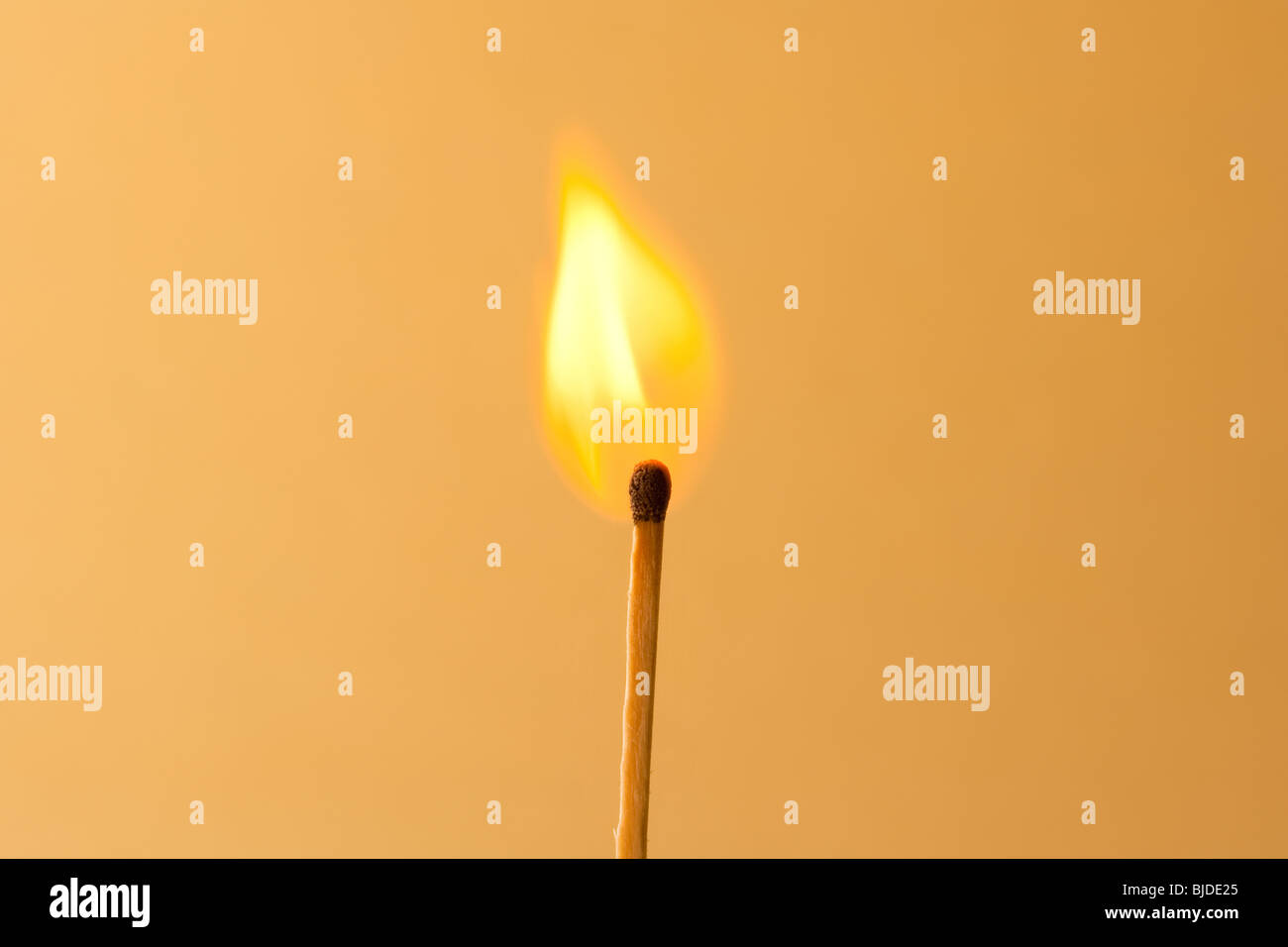 La masterizzazione di match contro un sfondo arancione Foto Stock