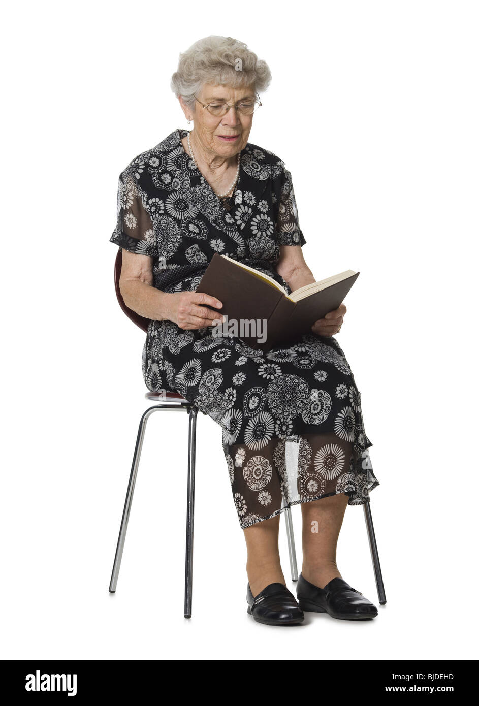 Senior donna seduta e la lettura di un libro. Foto Stock