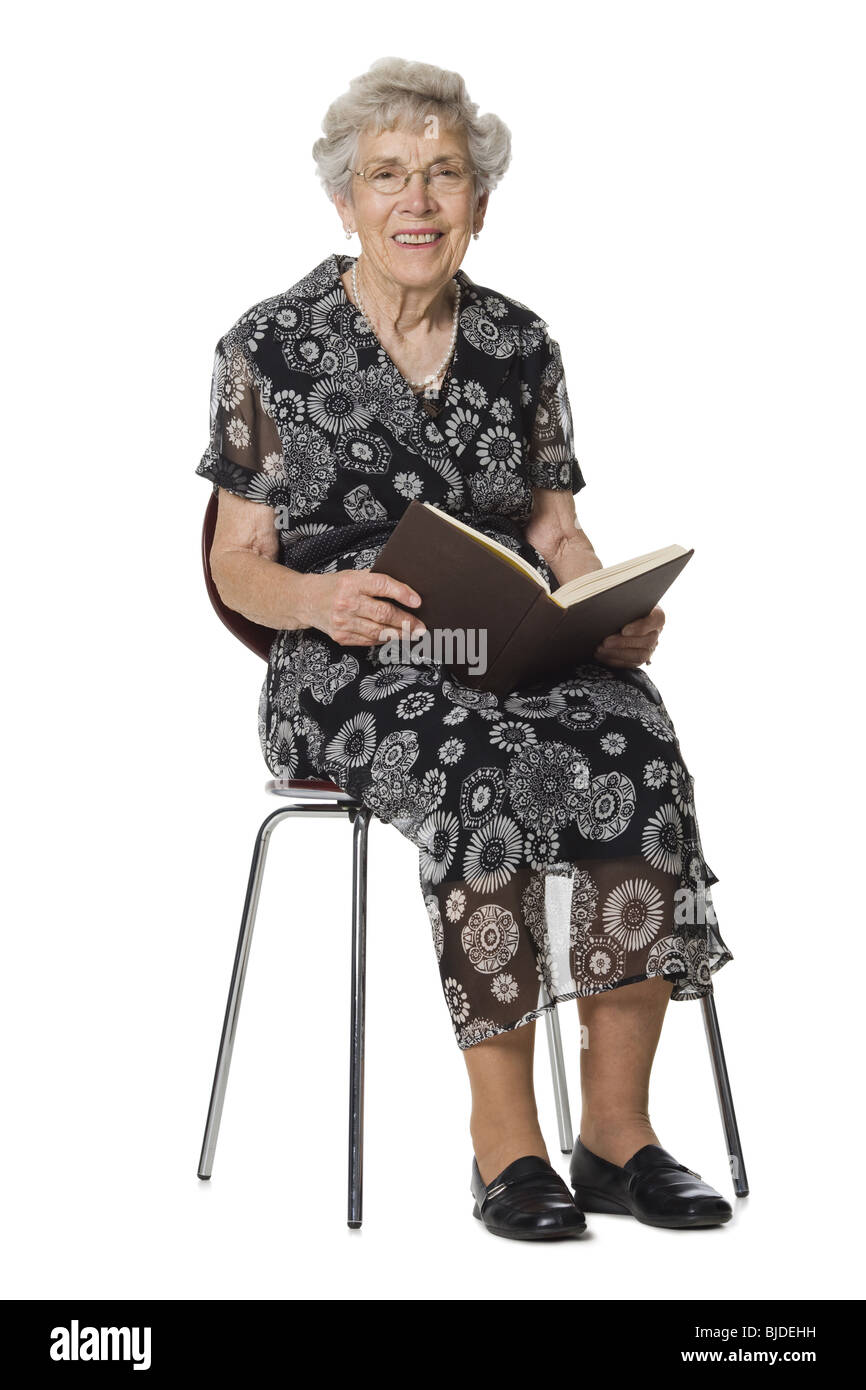 Senior donna seduta e la lettura di un libro. Foto Stock