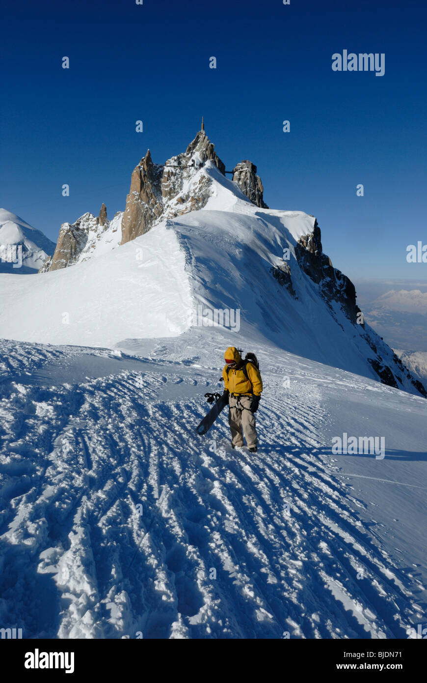 Snowboarder camminando sul crinale stretto da Aiguille du Midi verso le Vallee Blanche, Chamonix, Francia Foto Stock