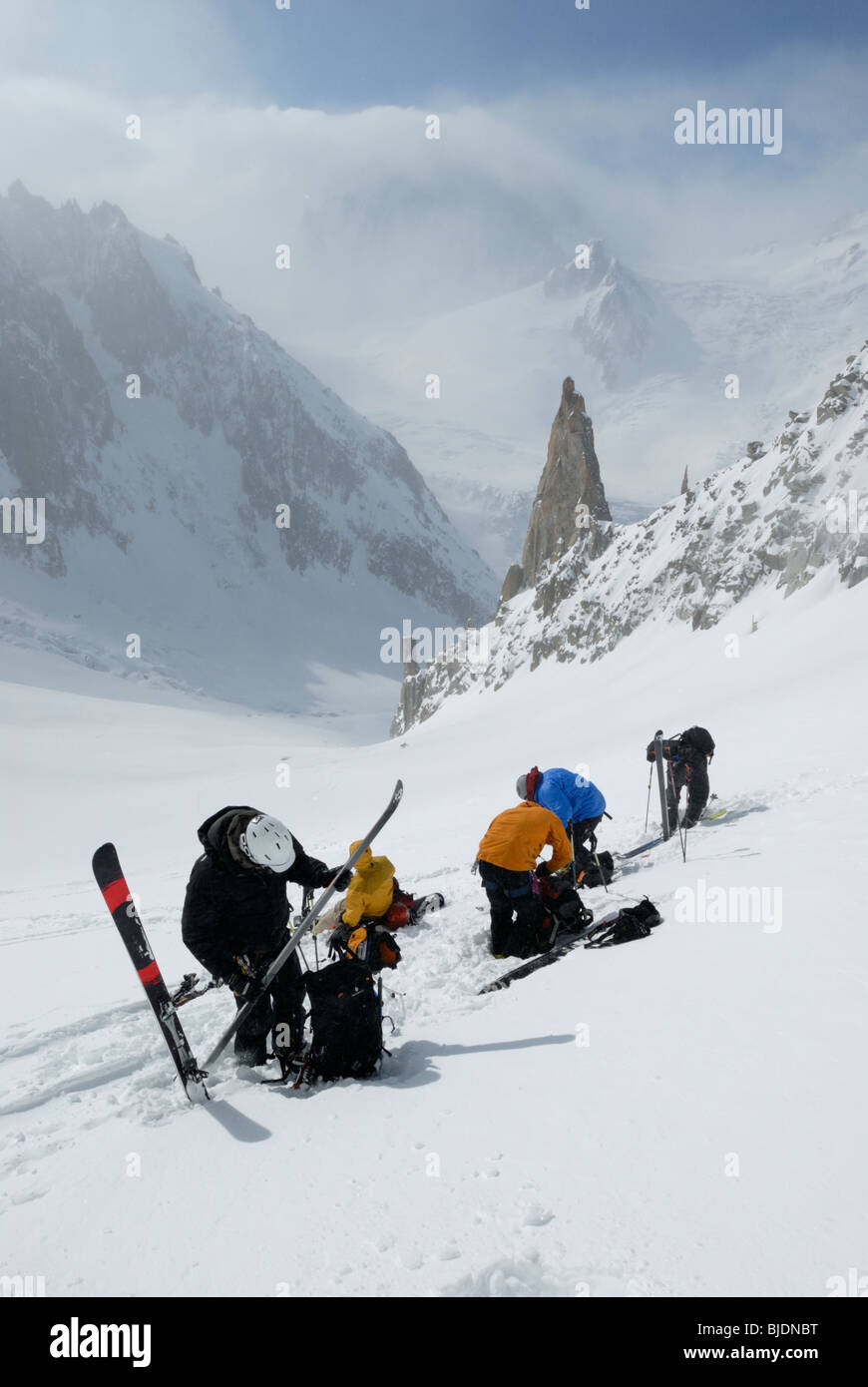 Gruppo di sciatori rimozione di pelli di arrampicata e di preparazione per la discesa. Massiccio del Monte Bianco e la Vallee Blanche in distanza. Foto Stock