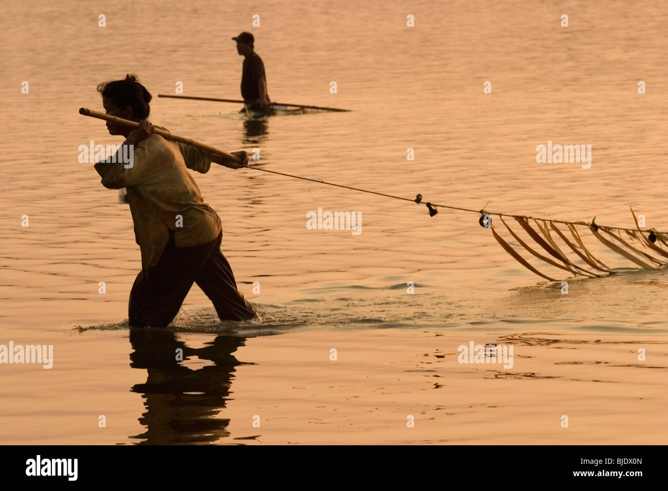 Una coppia di Lao utilizza una grande rete di pescare nei fondali del Fiume Mekong a Savannakhet, Repubblica Democratica Popolare del Laos. Foto Stock