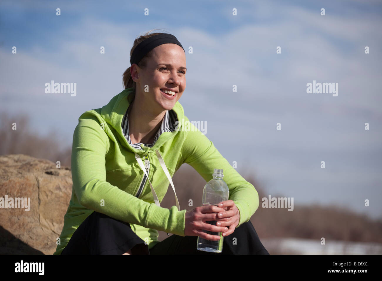 Donna felice rilassarsi all'aperto nel parco con bottiglia d'acqua Foto Stock
