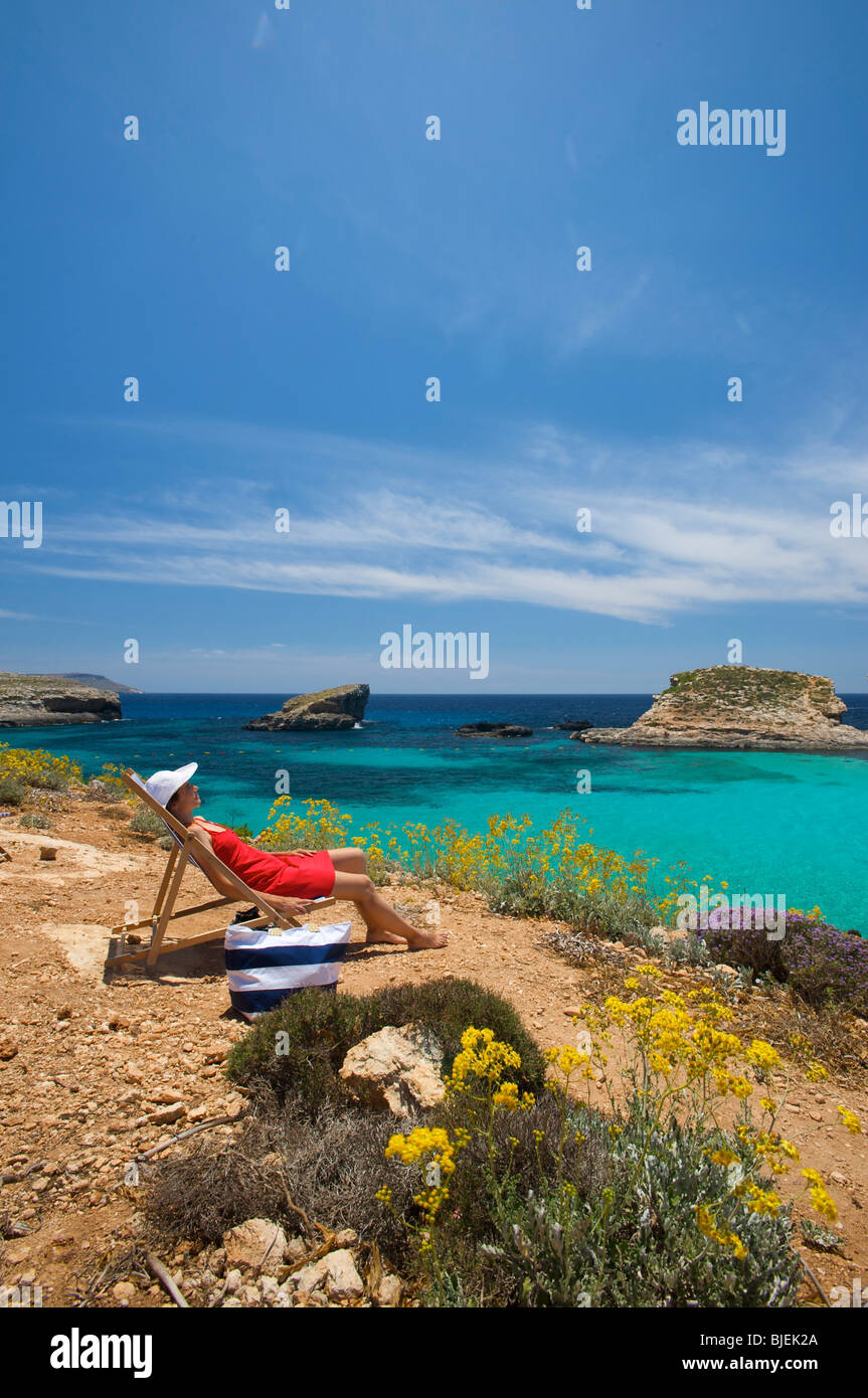 Donna seduta nel lettino, laguna blu a Comino e Malta Foto Stock