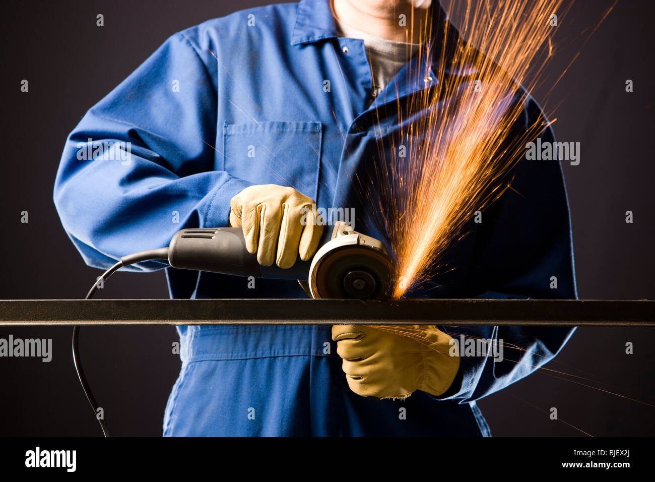 Uomo in tute blu con una smerigliatrice di potenza Foto Stock