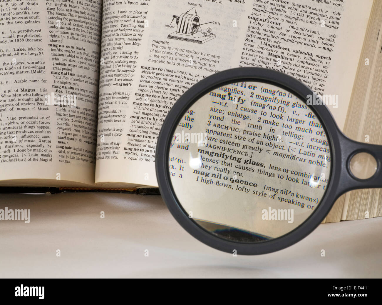 Una lente di ingrandimento sopra l'ingrandimento di parola in un dizionario di italiano Foto Stock