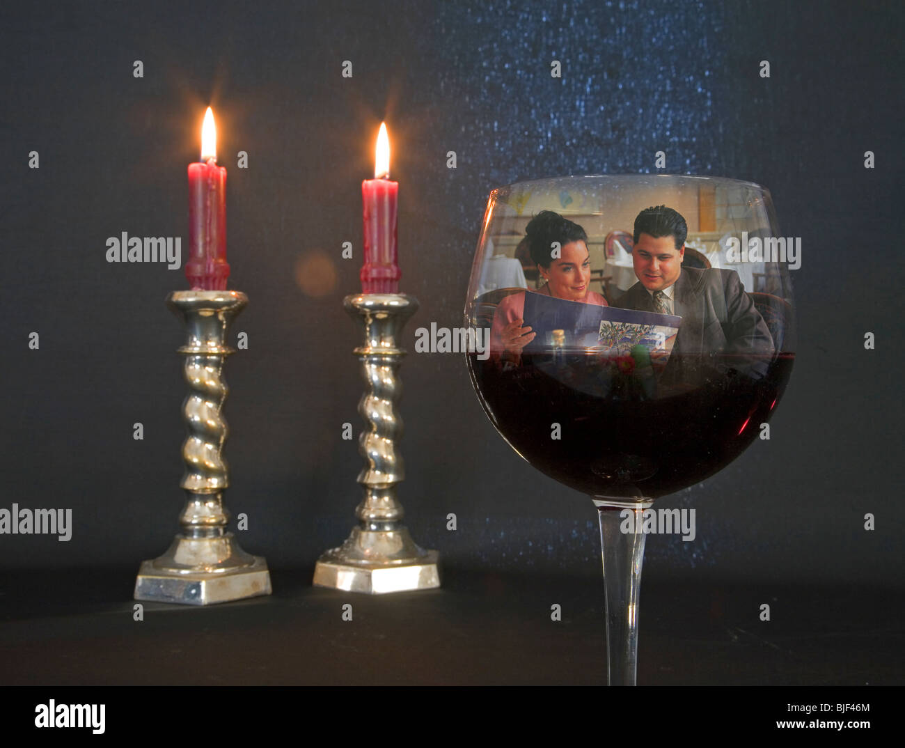 Candele accese, un bicchiere di rosso pino noir vino in una situazione romantica Foto Stock