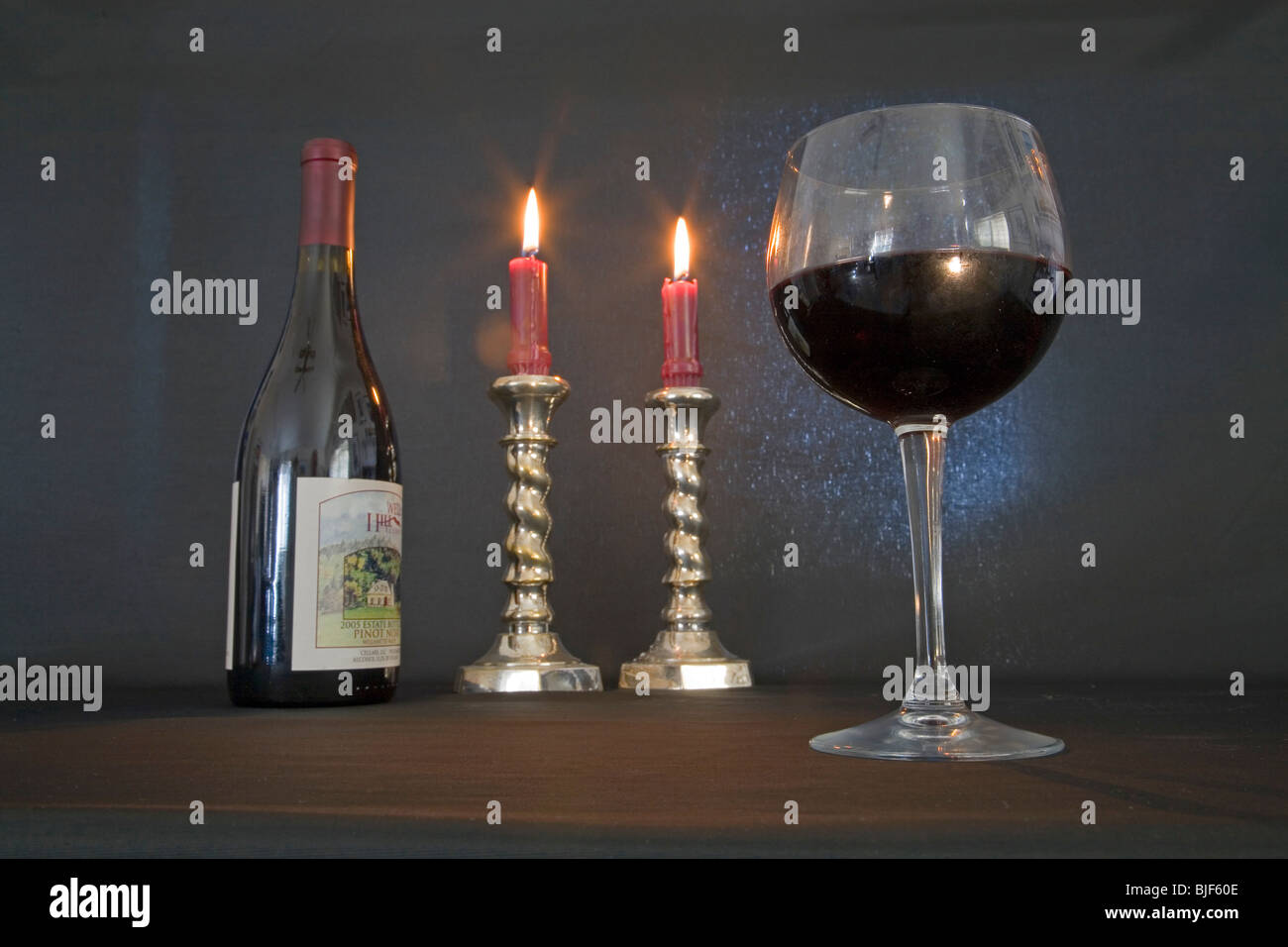 Candele accese, un bicchiere di rosso pino noir vino in una situazione romantica Foto Stock