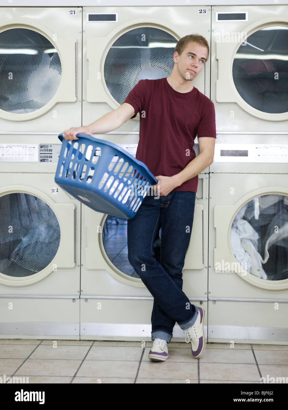 Uomo che fa servizio lavanderia in una lavanderia a gettoni Foto Stock