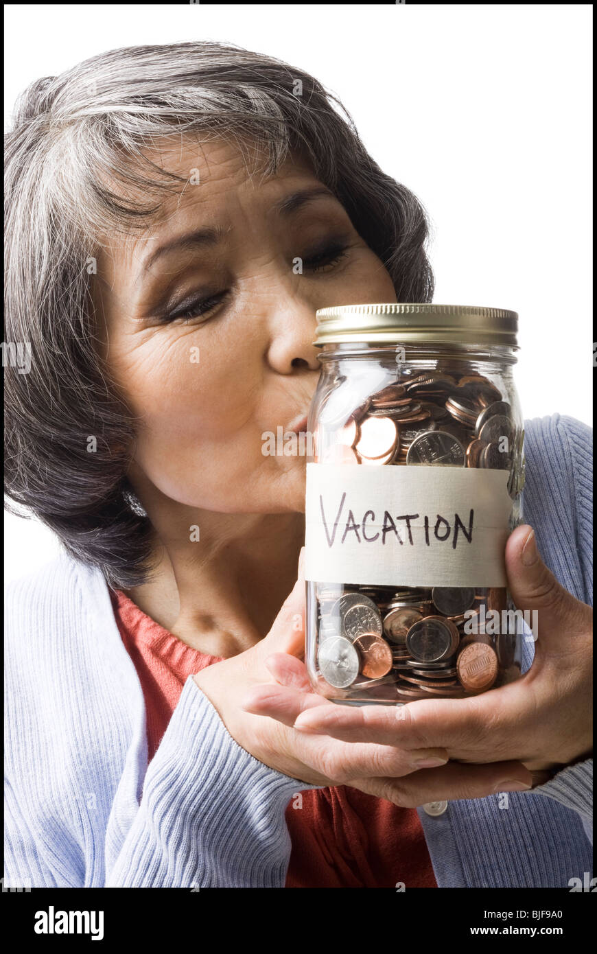 Una donna con un vaso pieno di monete Foto Stock