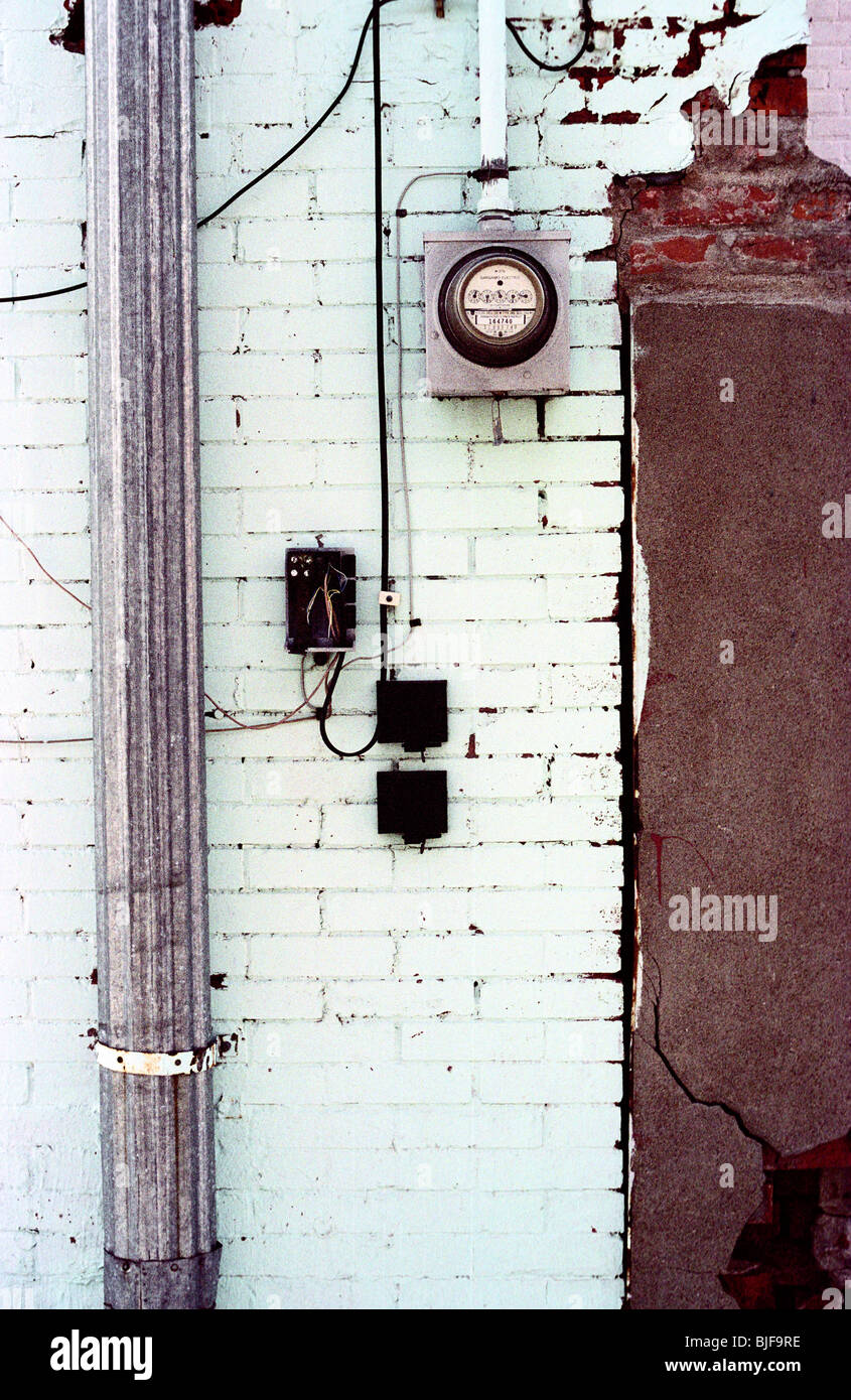 Un muro bianco e misuratore di potenza al di fuori in un vicoletto. Foto Stock