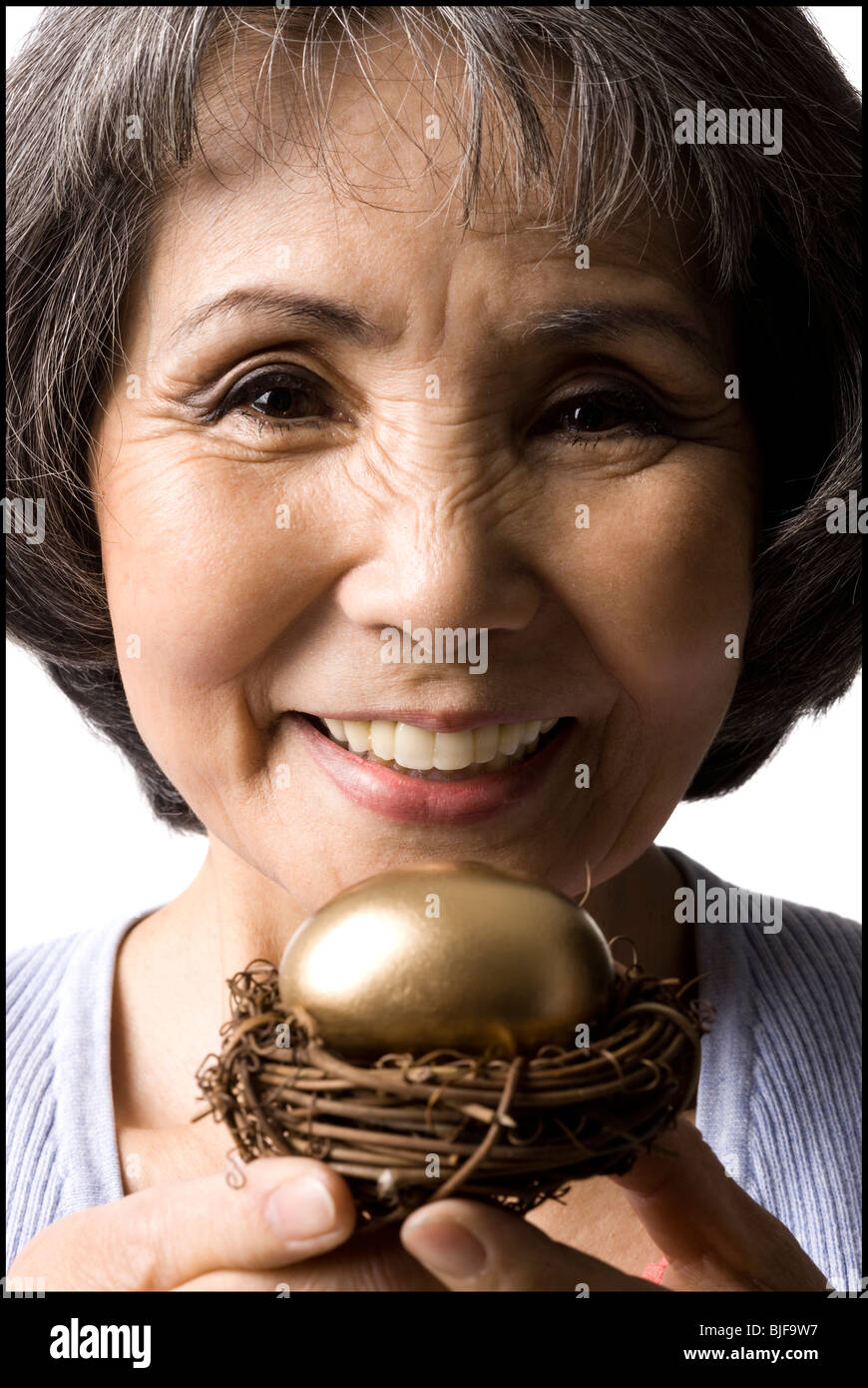 Senior donna tenendo un uovo dorato Foto Stock