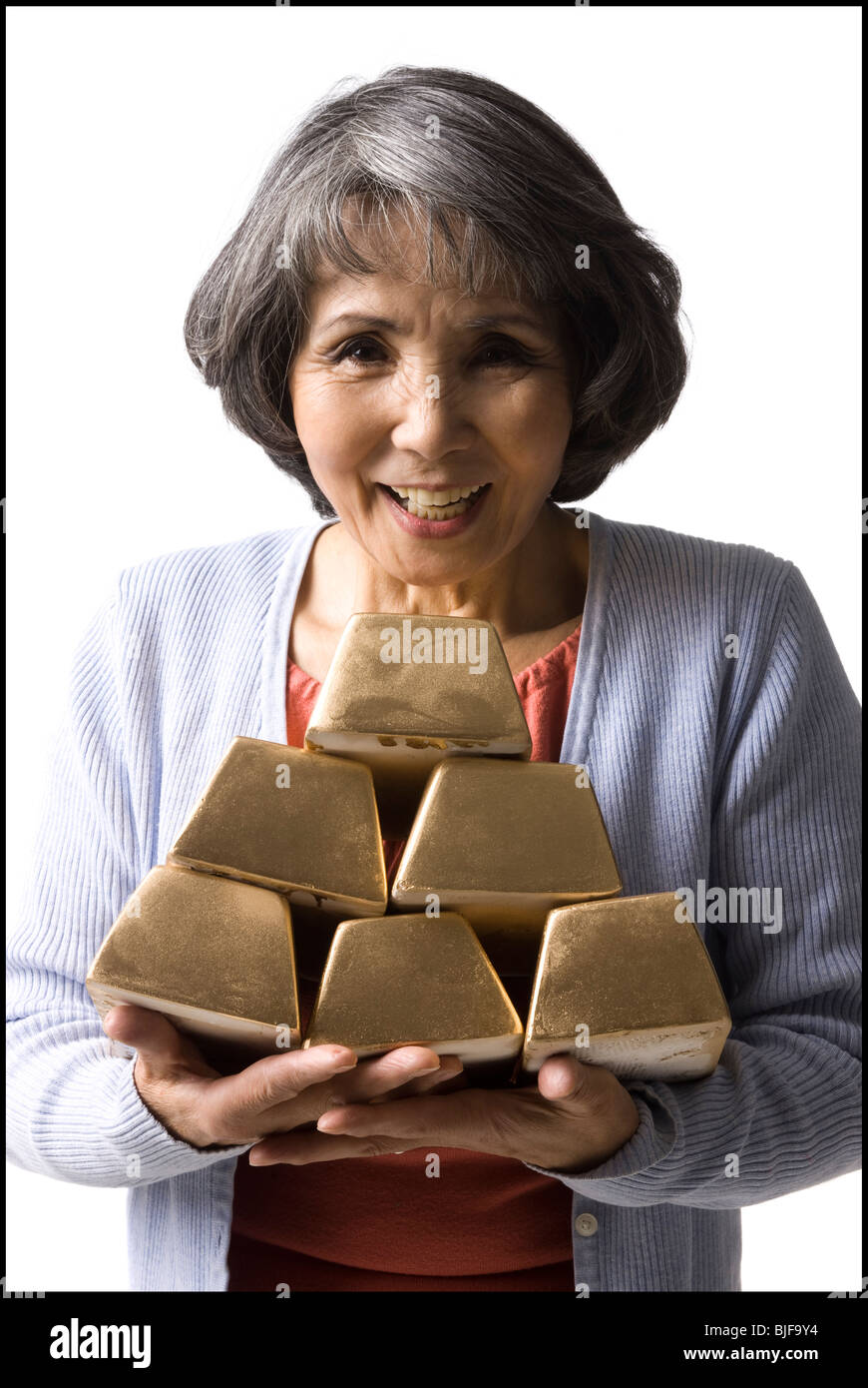 Donna senior in possesso di una pila di mattoni in oro Foto Stock