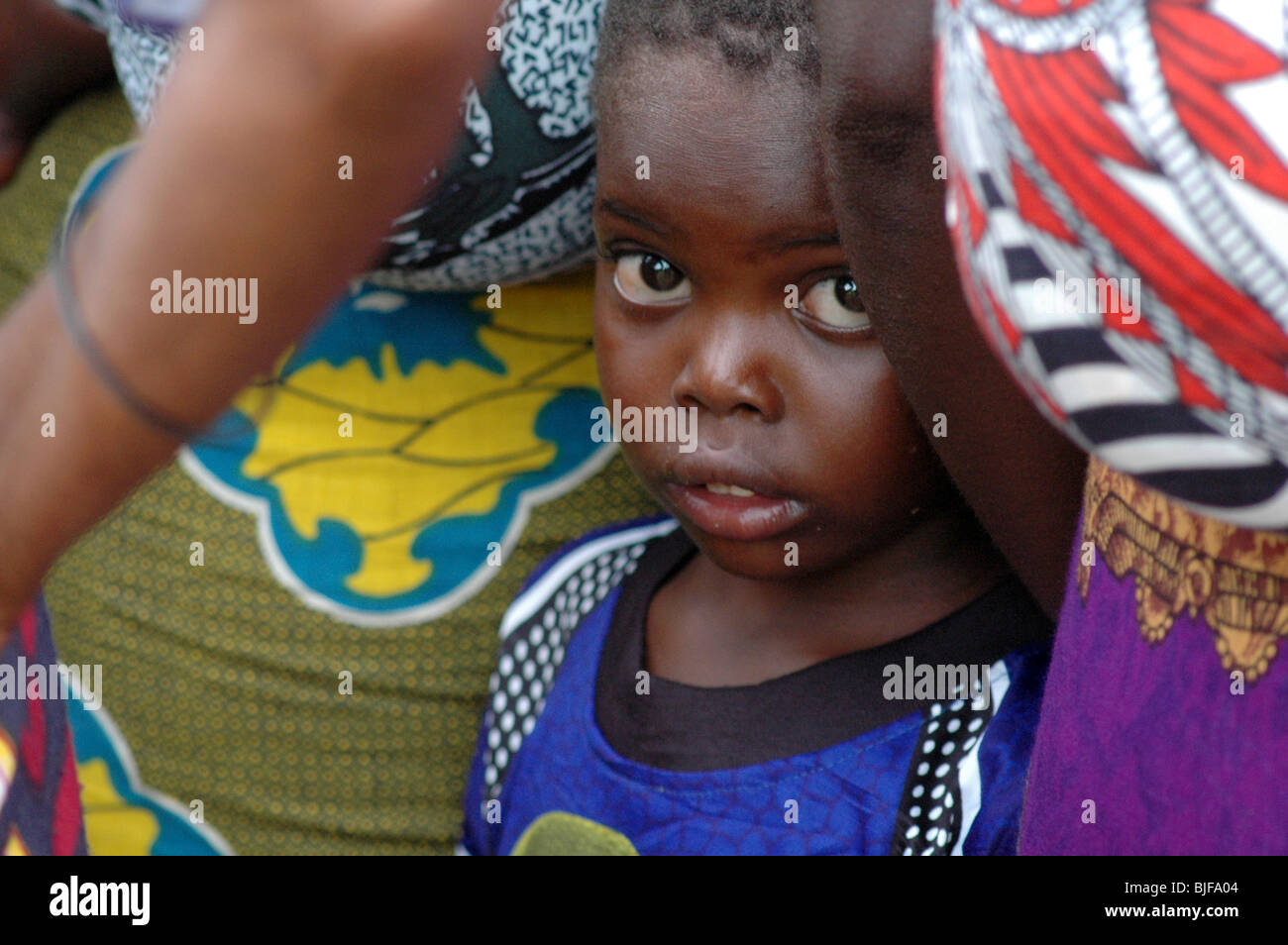 Un giovane ragazzo in piedi dal suo lato delle madri. Il Malawi, Africa Foto Stock