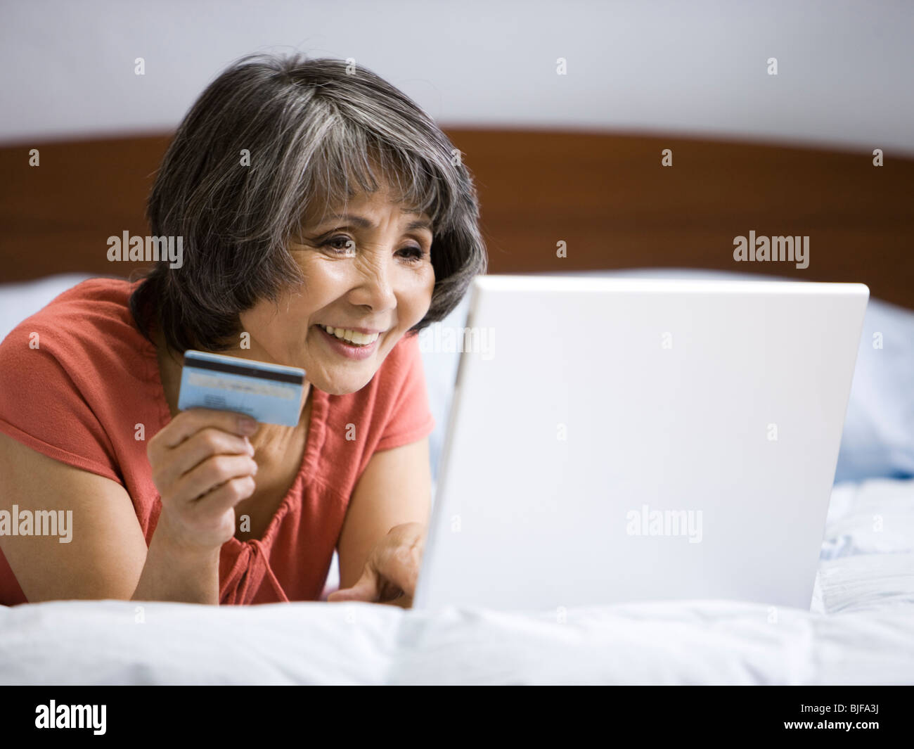 Senior donna fare un acquisto online con la sua carta di credito Foto Stock
