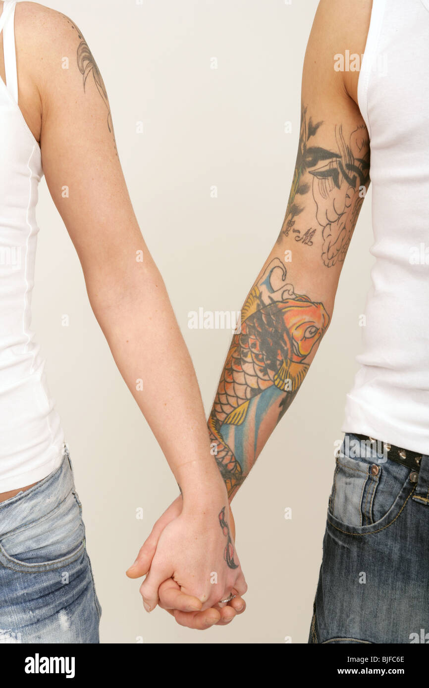 Maschio e femmina bracci tatuati tenendo le mani. Foto Stock
