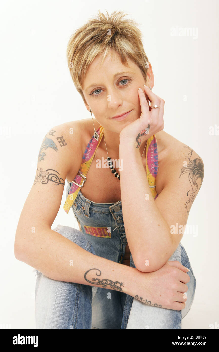 Tatuato donna seduta salopette da indossare Foto Stock