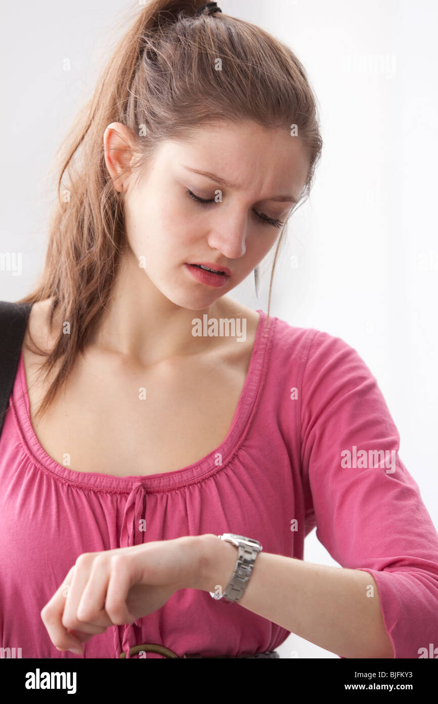 Ragazza adolescente è scosso da tempo sul suo orologio Foto Stock