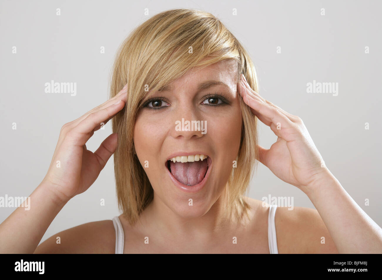 Una donna che grida con le sue dita premuto contro la sua testa. Foto Stock