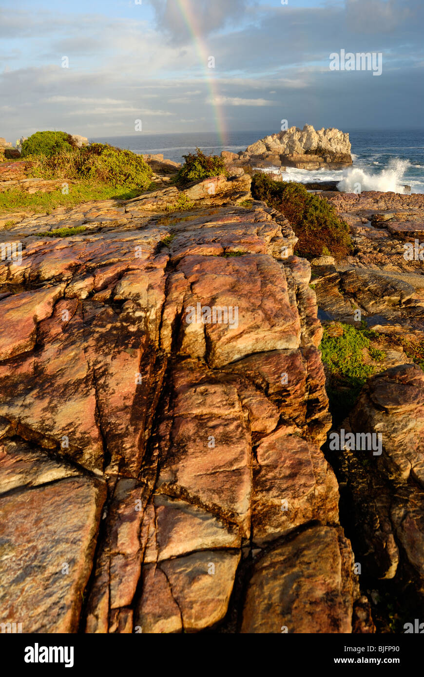 Rainbow su Ocean da una costa rocciosa, tramonto, Hermanus, South Western Cape, Sud Africa Foto Stock