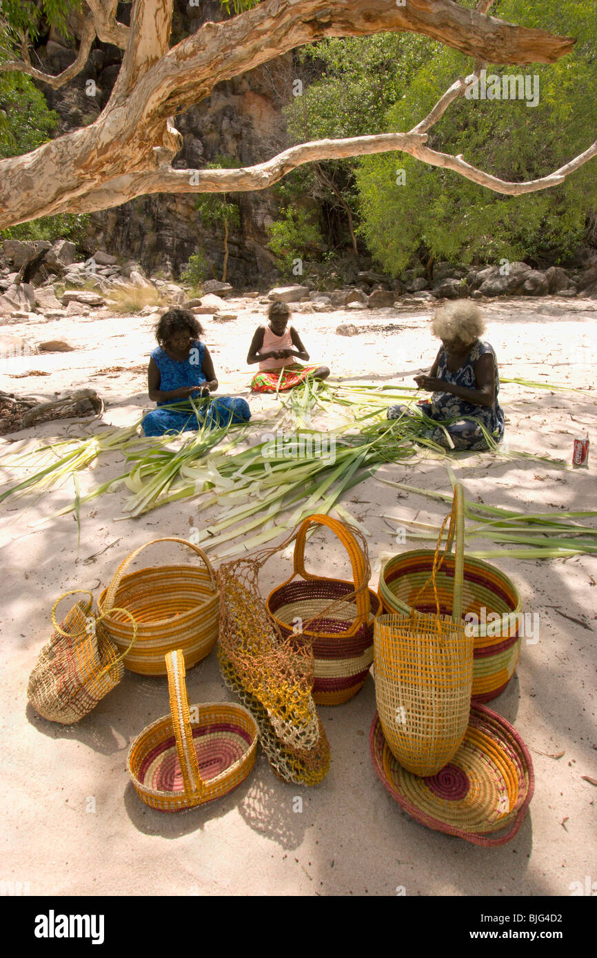 Aboriginal artigiane in dry creekbed pandanus sdoppiamento di colorante secca e intreccio cesti & dilly-sacchetti per la vendita a Injalak . Foto Stock