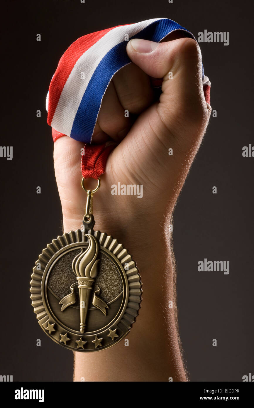 Mano che tiene una medaglia d'oro Foto Stock