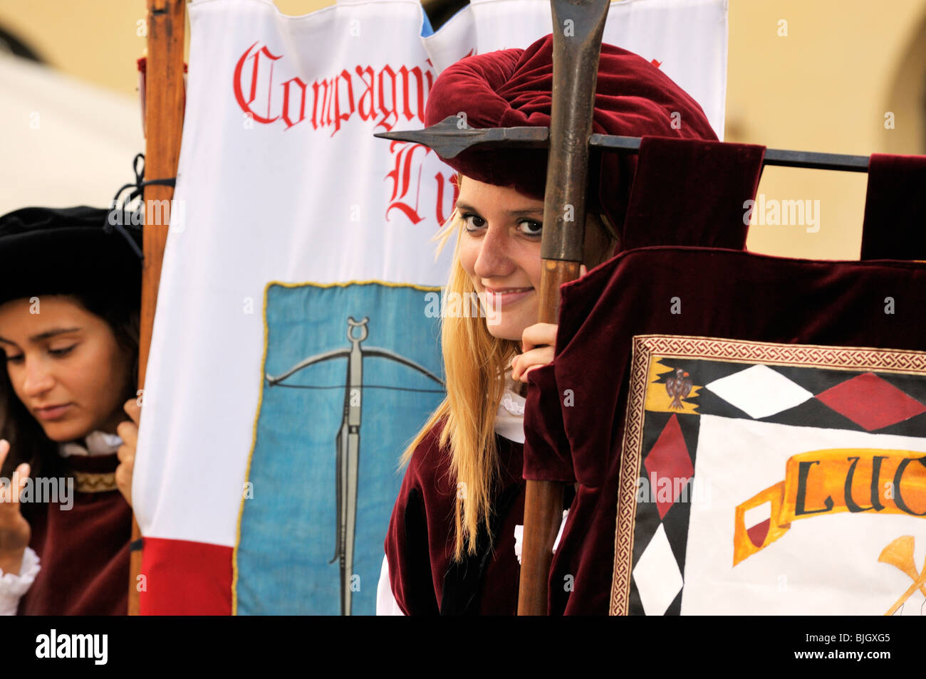 Città italiana di Lucca. Giovani donne locali portano i banner in costume medievale street pageant festival. Toscana, Italia Foto Stock