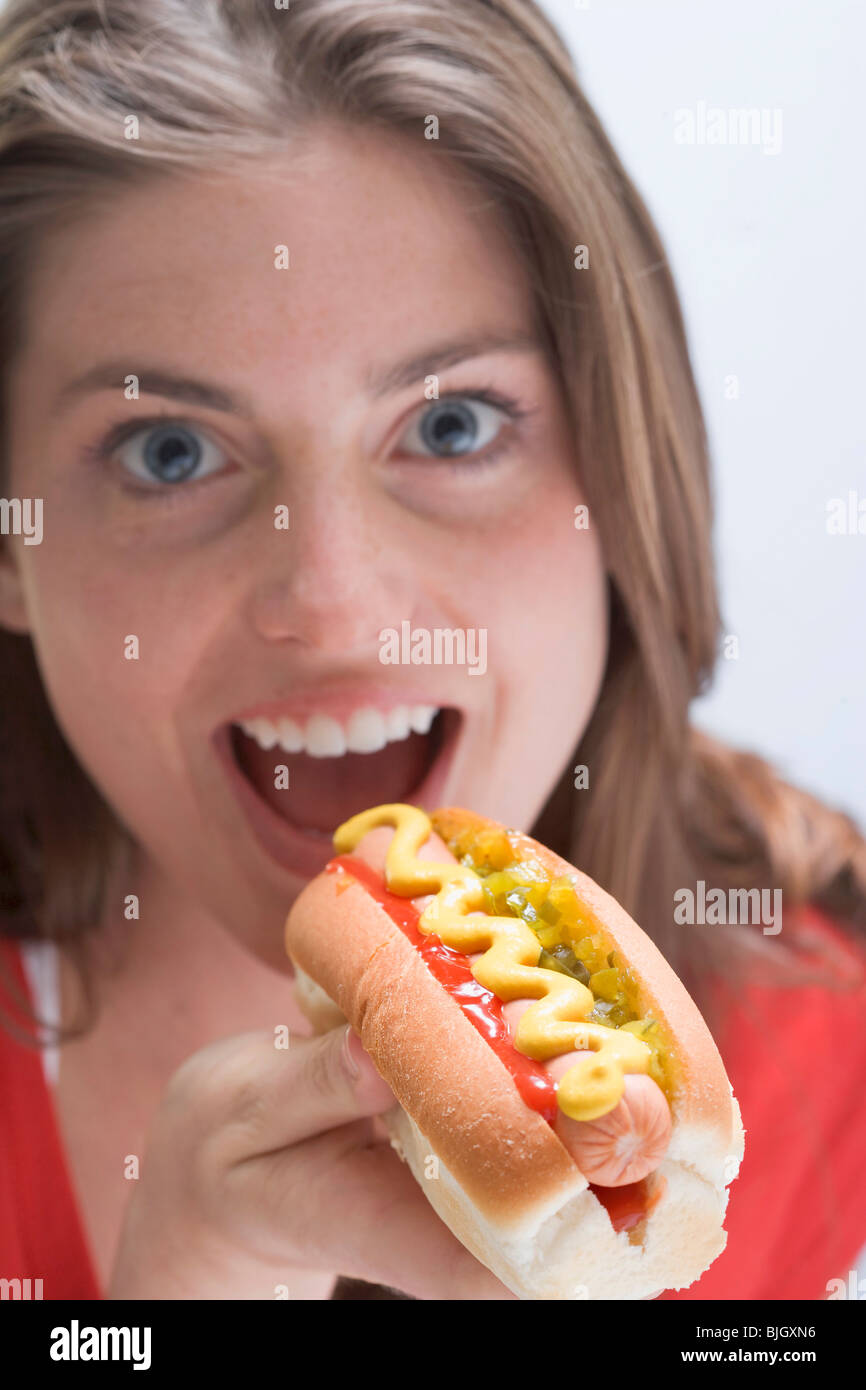 Donna di mangiare un hot dog con senape - Foto Stock