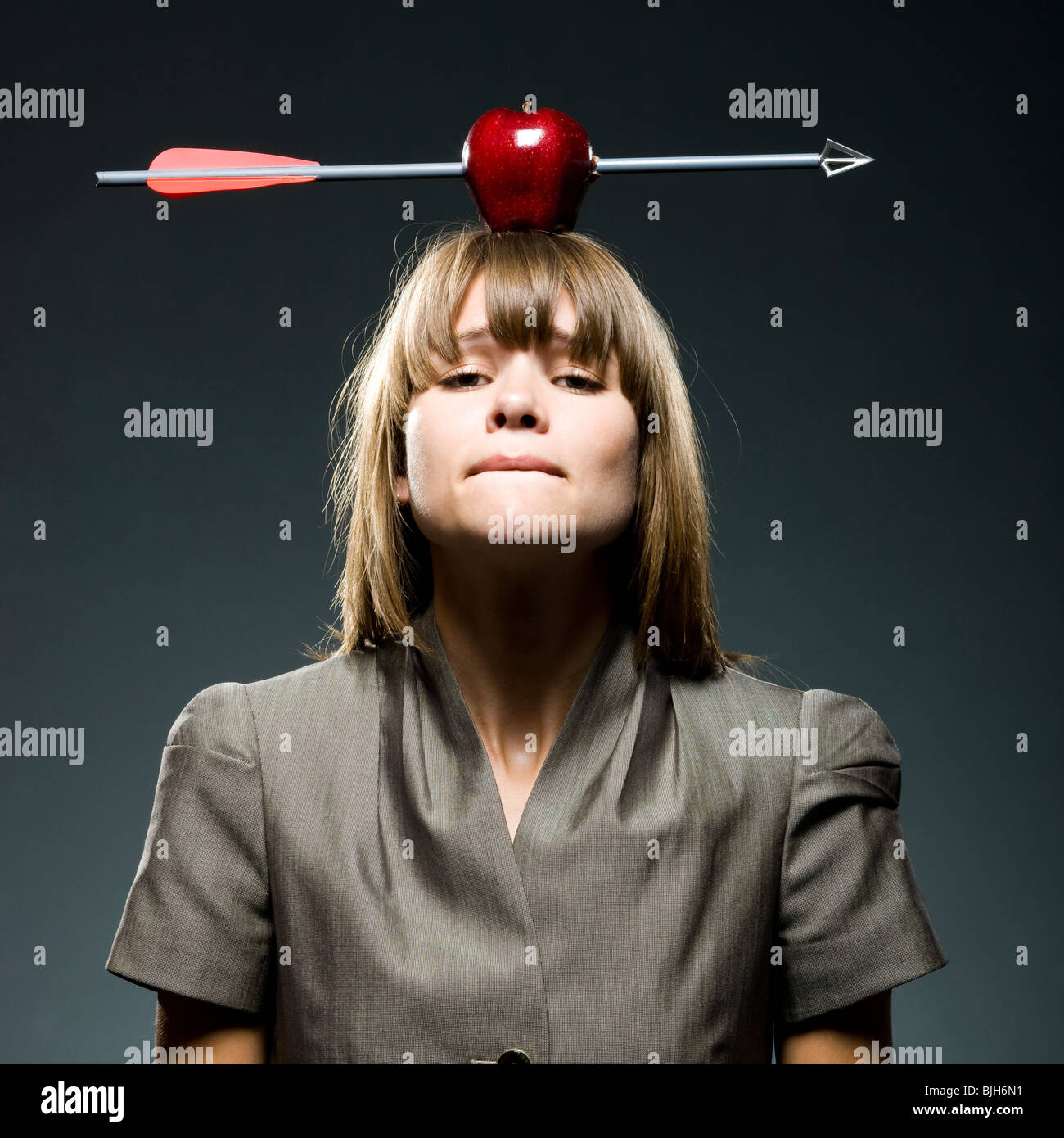 Imprenditrice con un Apple con una freccia attraverso di esso sulla sua testa Foto Stock