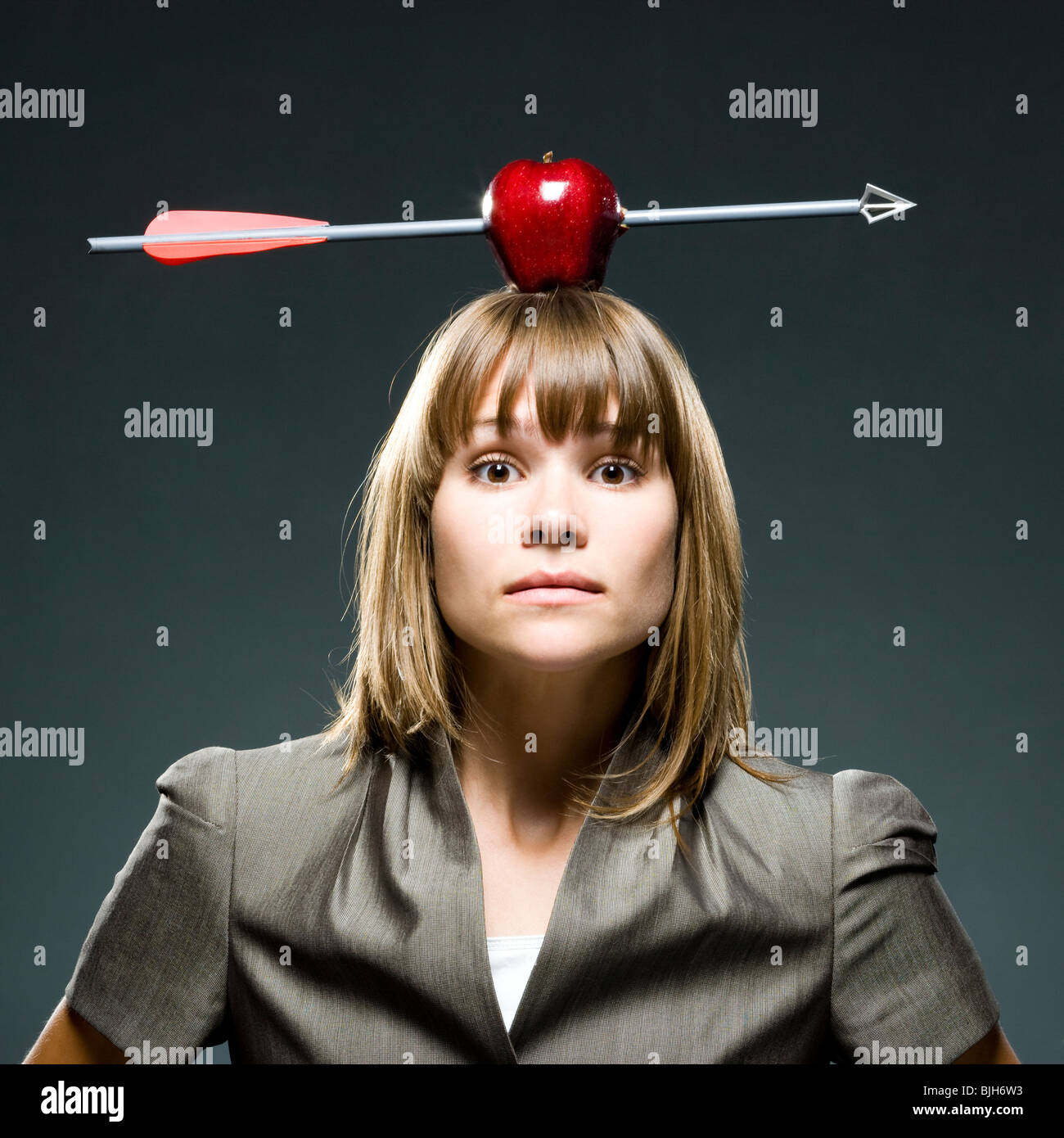 Imprenditrice con un Apple con una freccia attraverso di esso sulla sua testa Foto Stock