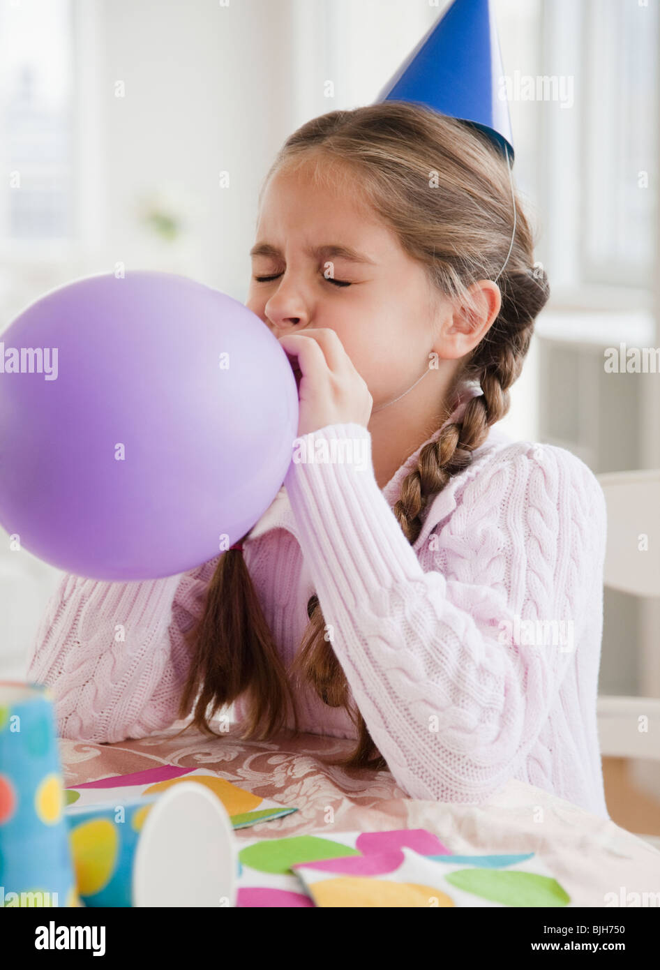 Giovane ragazza che soffia su palloncino Foto Stock
