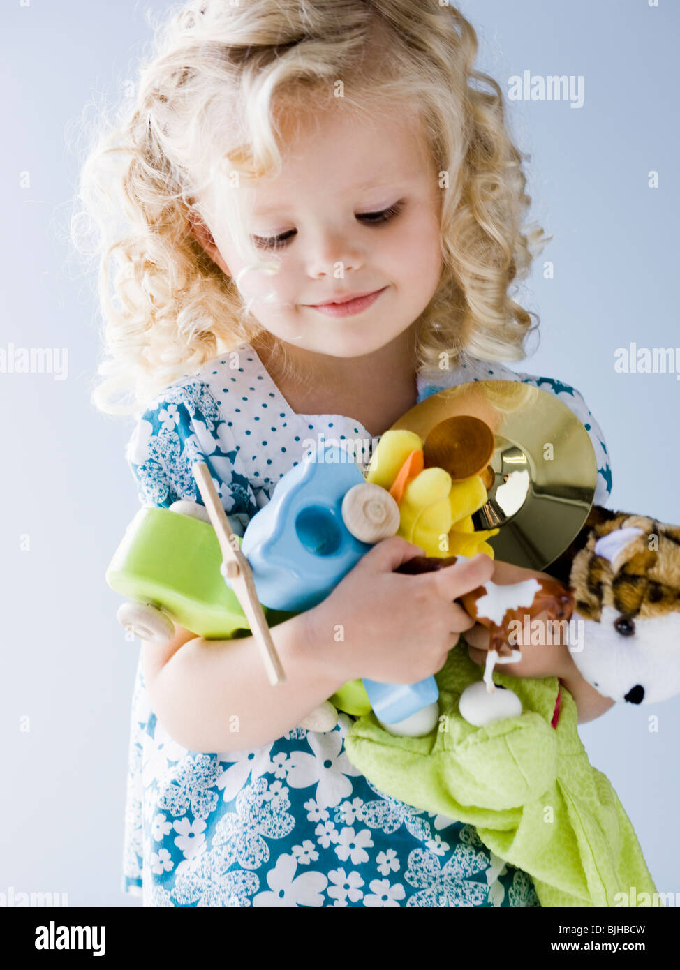 Bambina tenendo una bracciata dei suoi giocattoli Foto Stock
