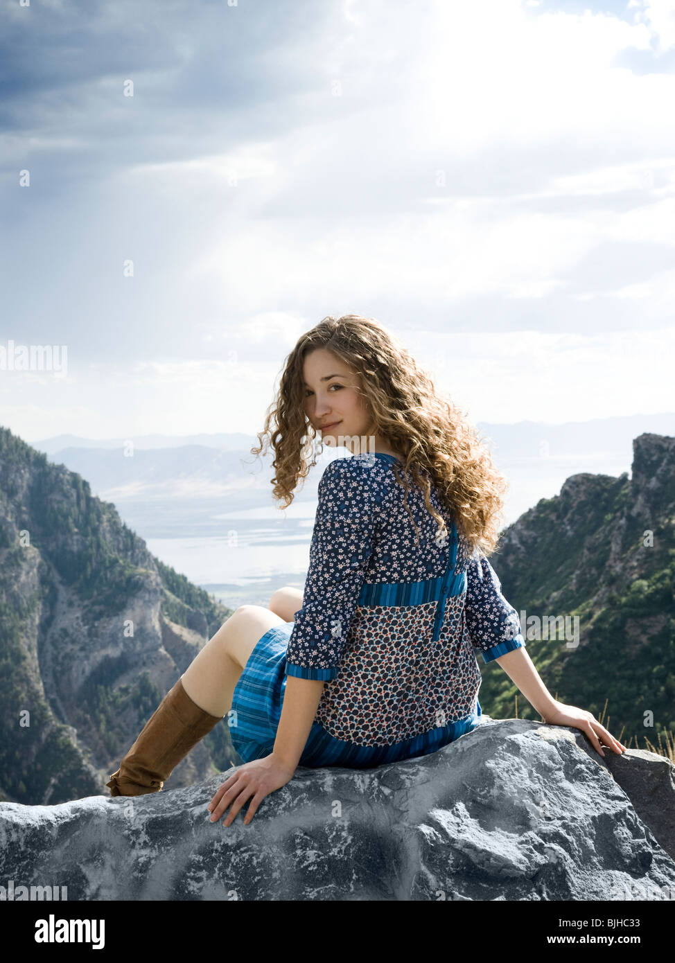 La donna in una stampa floreale abito in cima a una montagna seduto su una roccia Foto Stock