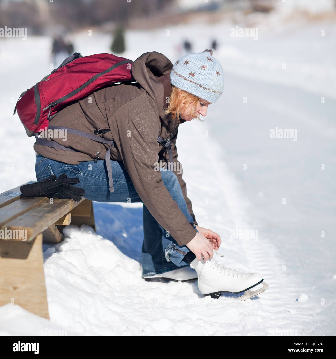 Donna allacciamento i suoi pattini da ghiaccio all'aperto, Assiniboine River Trail, Winnipeg, Manitoba, Canada. Foto Stock