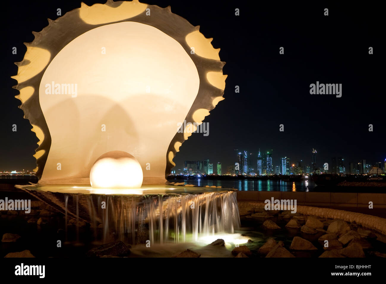 La Perla e Oyster fontana sulla Corniche a Doha, in Qatar di notte. La skyline di Doha è visibile in background. Foto Stock