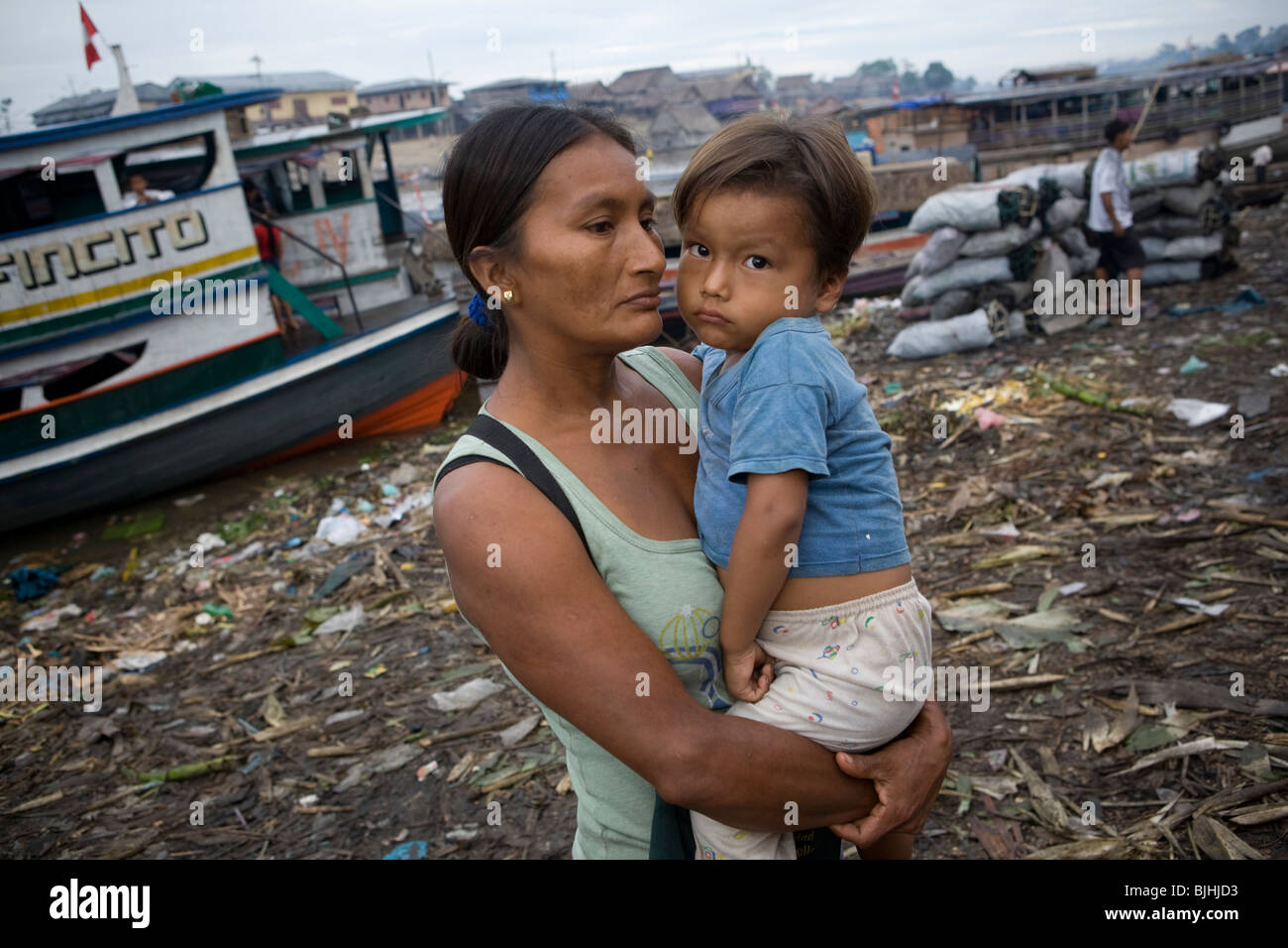 Una donna che tiene il suo ragazzo giovane lungo le rive del fiume in Puerto Belen, Iquitos, Perù il bacino amazzonico. Foto Stock