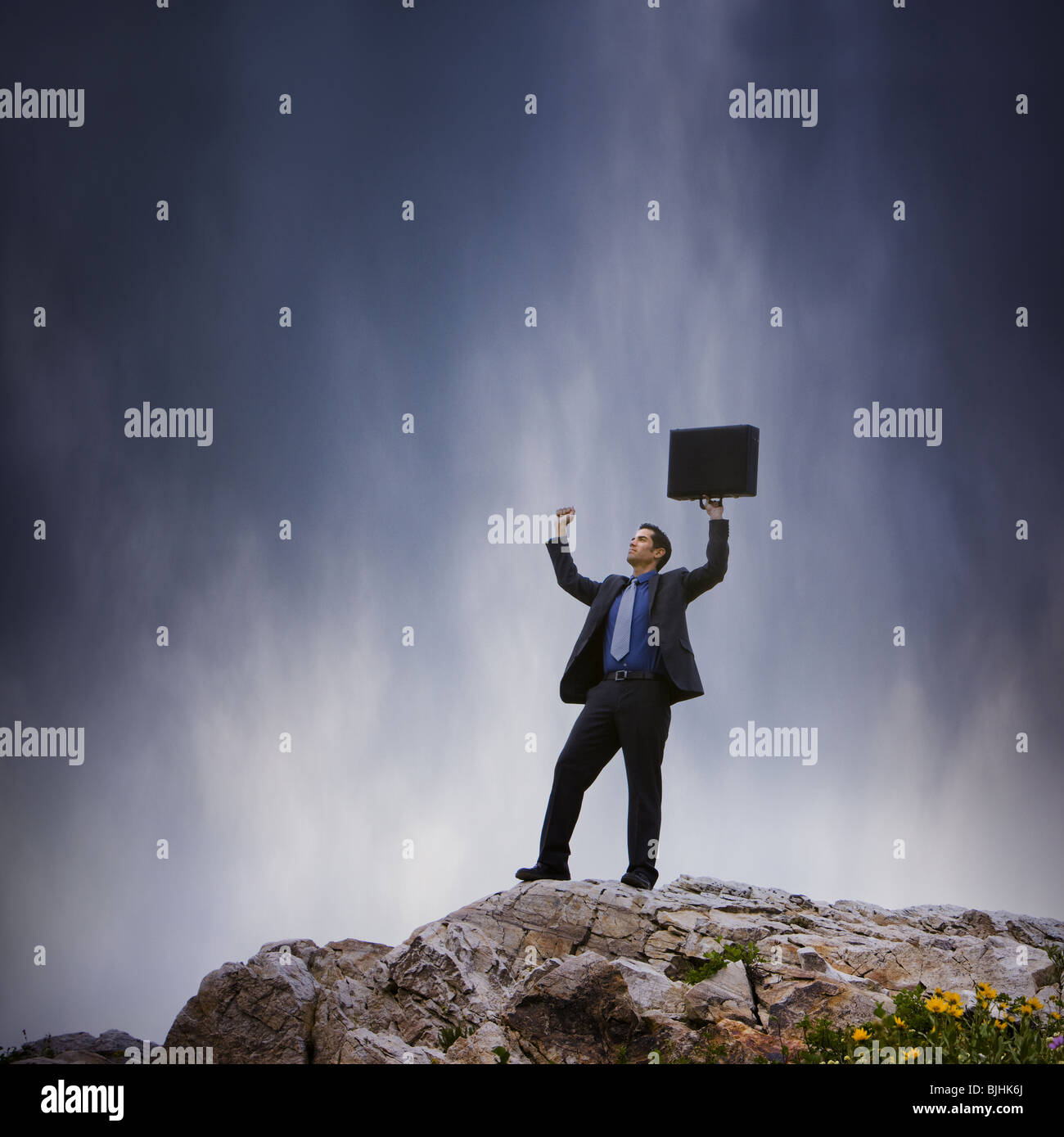 Imprenditore tenendo le braccia in aria sulla cima di una scogliera Foto Stock