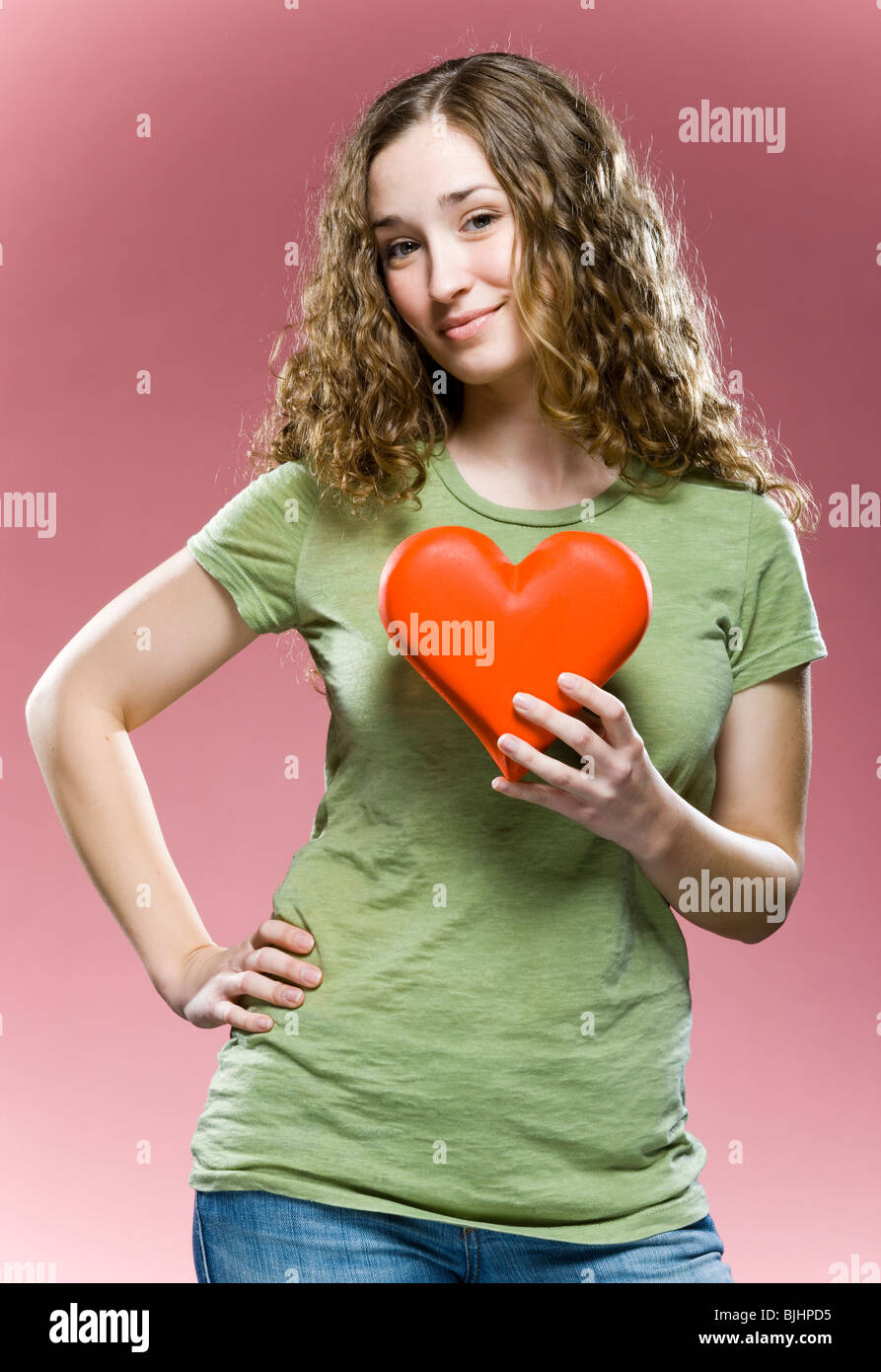 Donna che mantiene un cuore per il suo torace Foto Stock