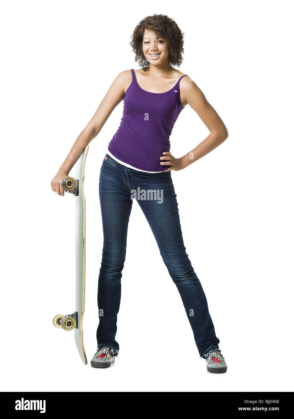 Ragazza permanente e la holding skateboard Foto Stock