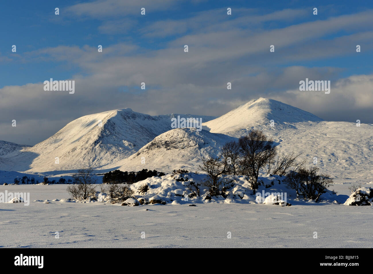 Struttura rocciosa-isola ricoperta in frozen coperte di neve sul lago con sfondo innevato delle montagne e il cielo blu scuro Foto Stock