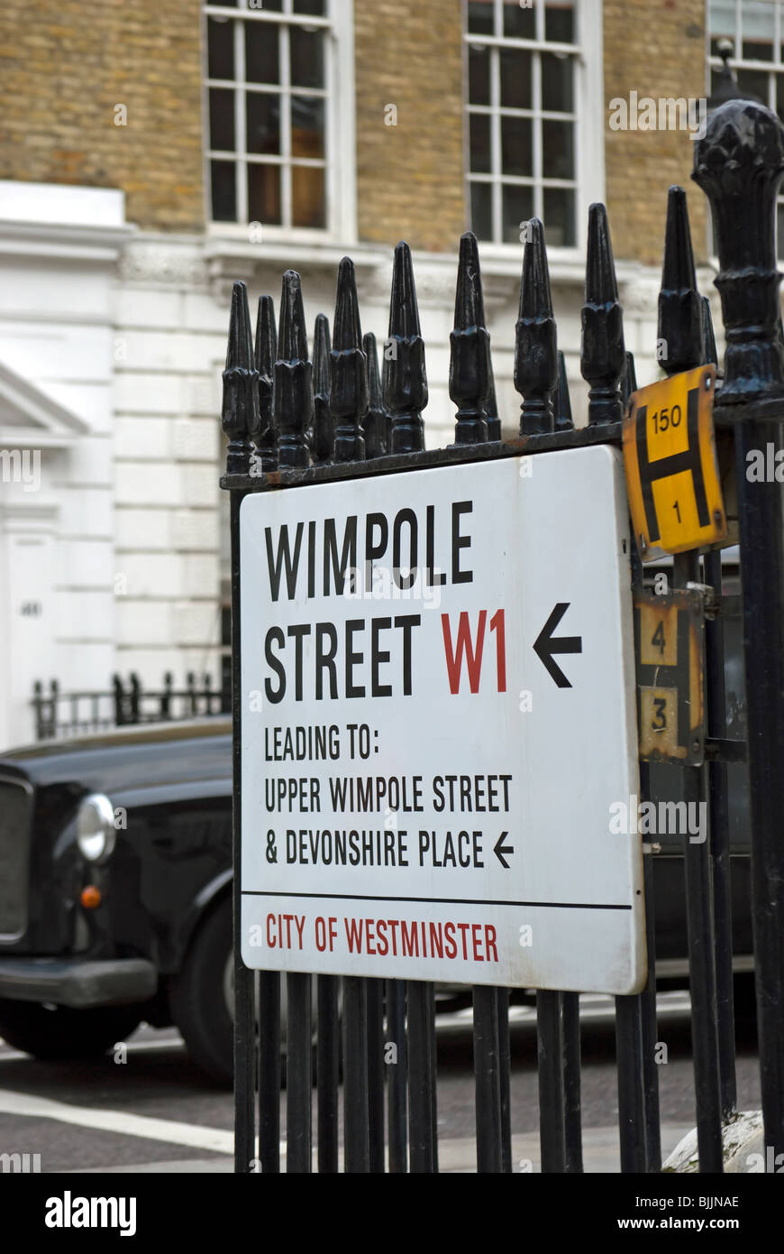 Un cartello stradale su Wimpole Street, London W1, Inghilterra, con taxi a Londra in background Foto Stock